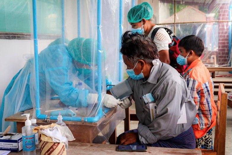 Volunteer tests blood pressure of a coronavirus disease (COVID-19) patient in the town of Kale, Sagaing Region, Myanmar