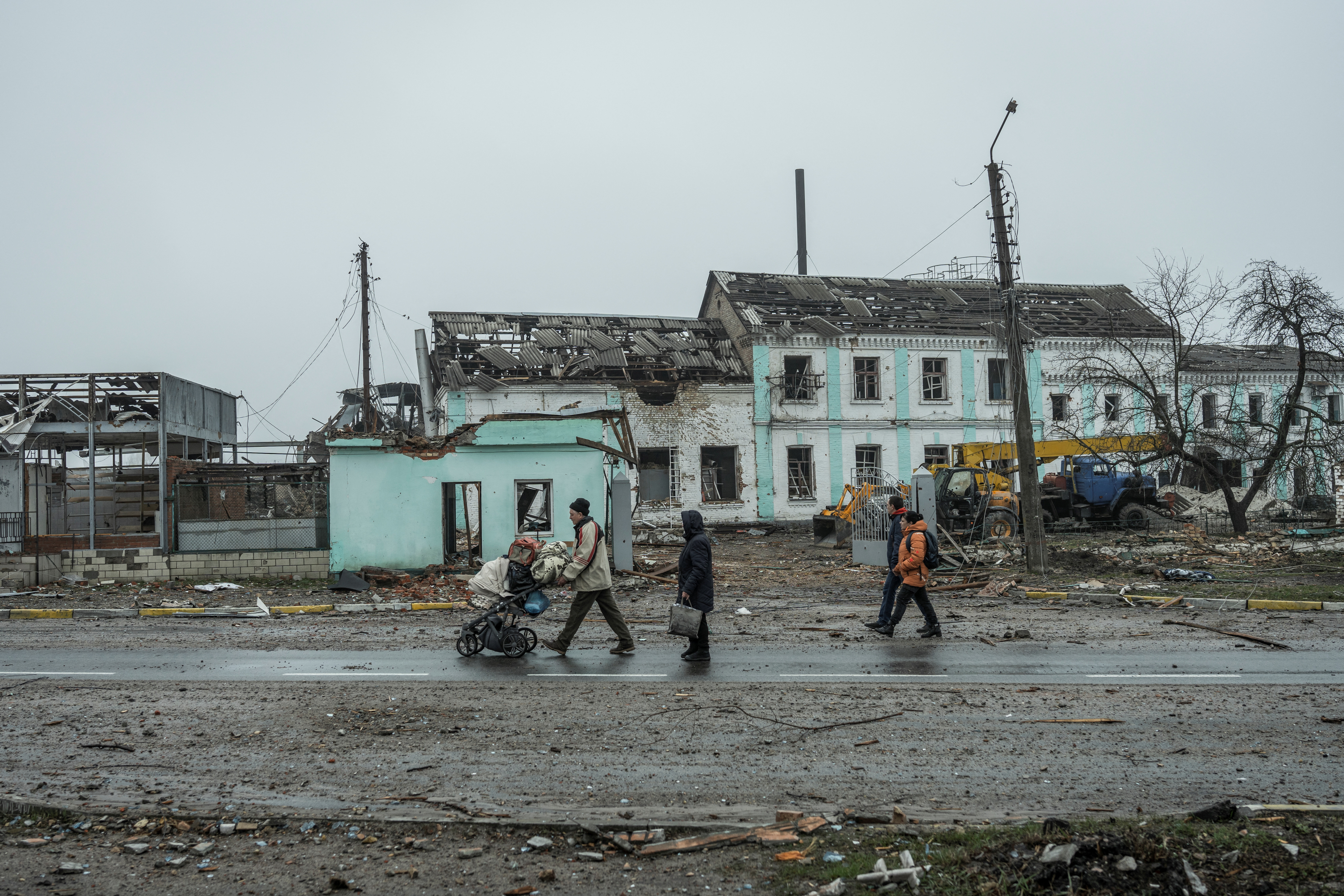 I residenti locali passano davanti agli edifici danneggiati dai bombardamenti nella città di Makariv