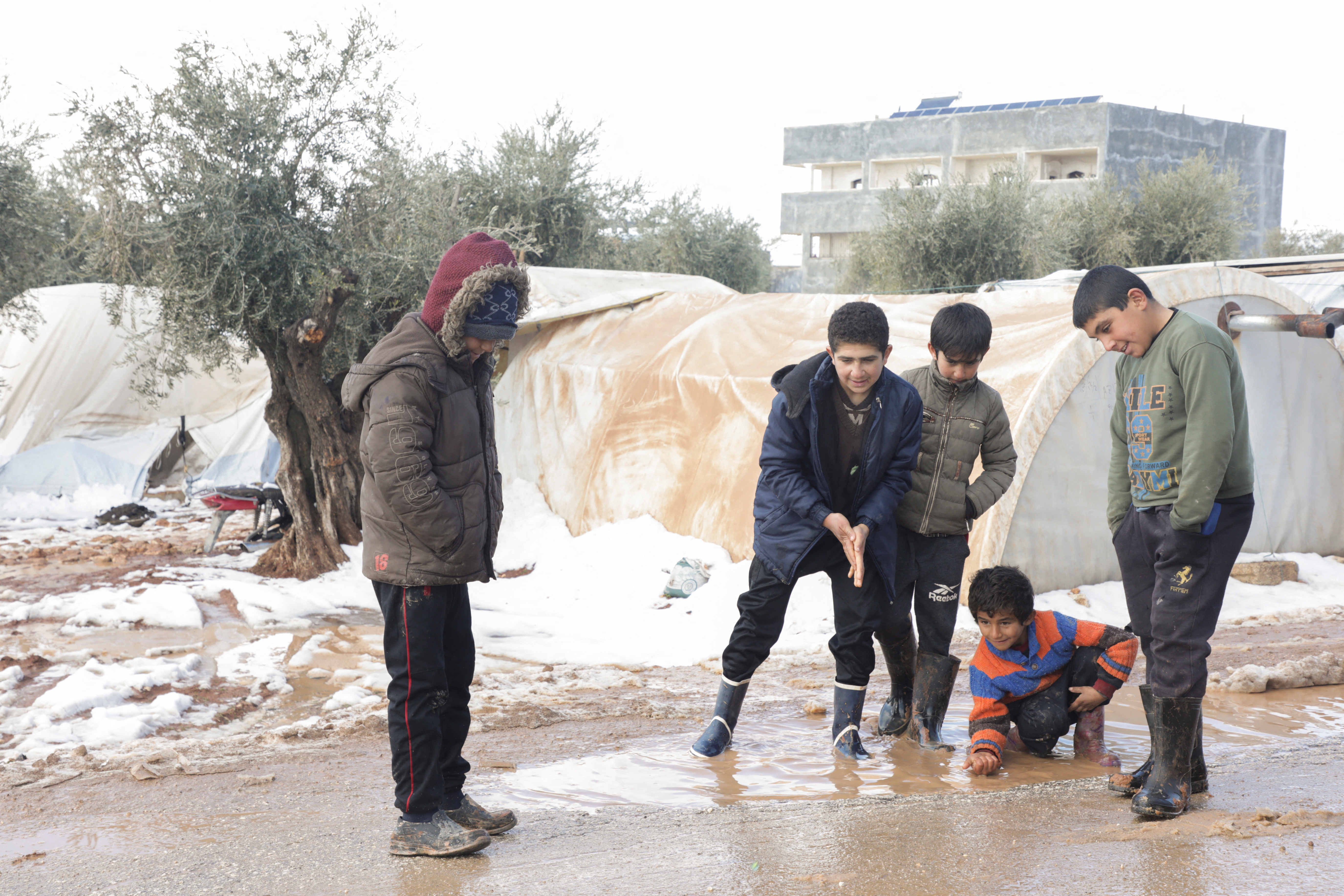 Internally displaced boys play together at a snow covered camp in the Aleppo countryside