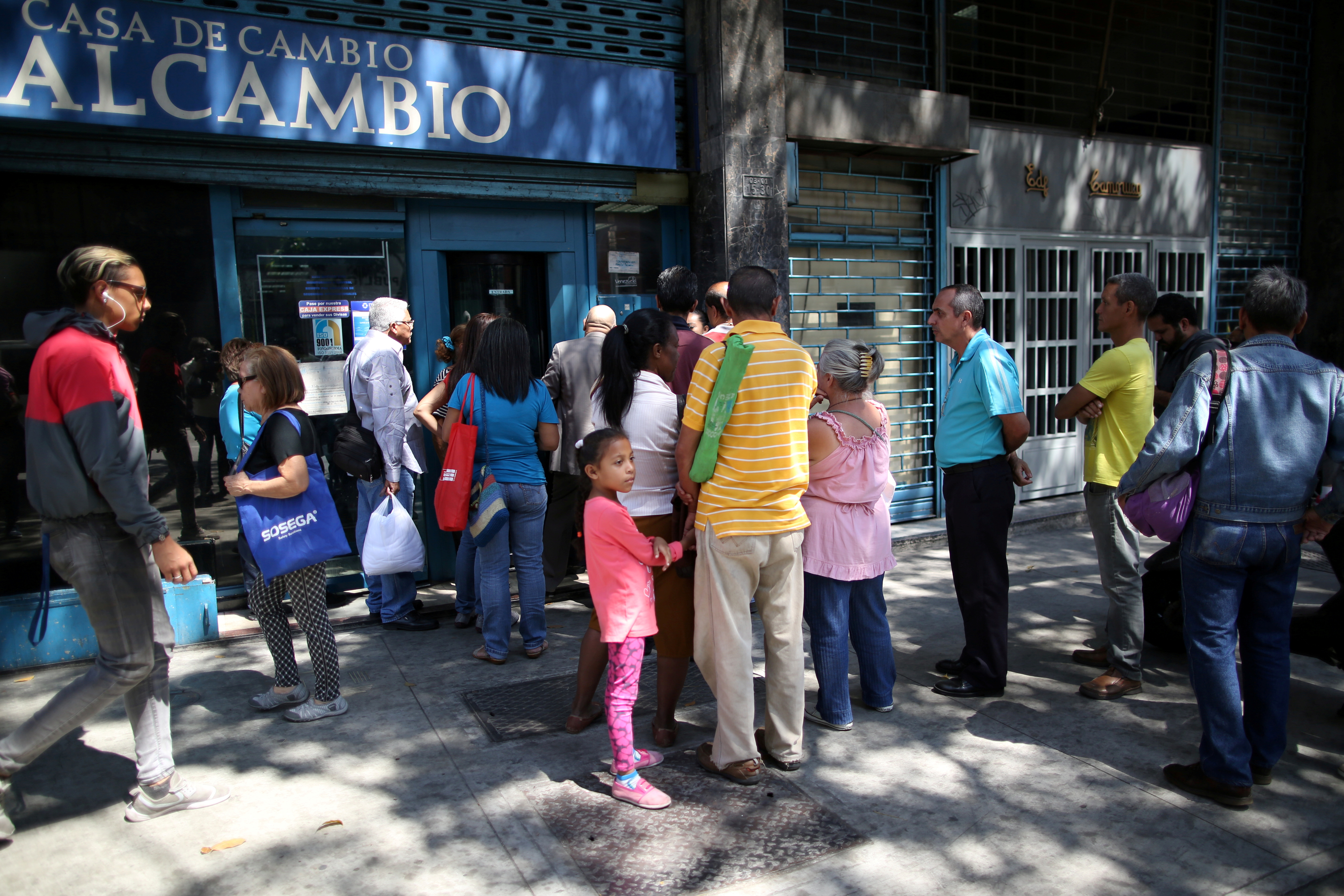 People wait in line outside of a currency exchange house in Caracas