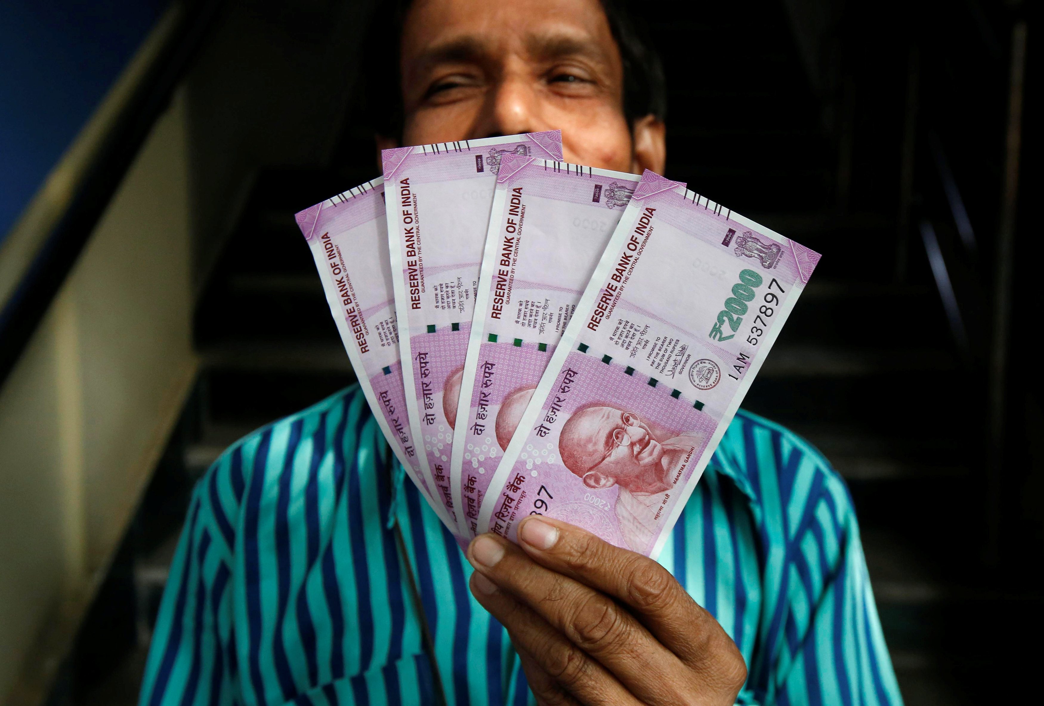 A man displays new 2000 Indian rupee banknotes after withdrawing them from a State Bank of India branch in Kolkata
