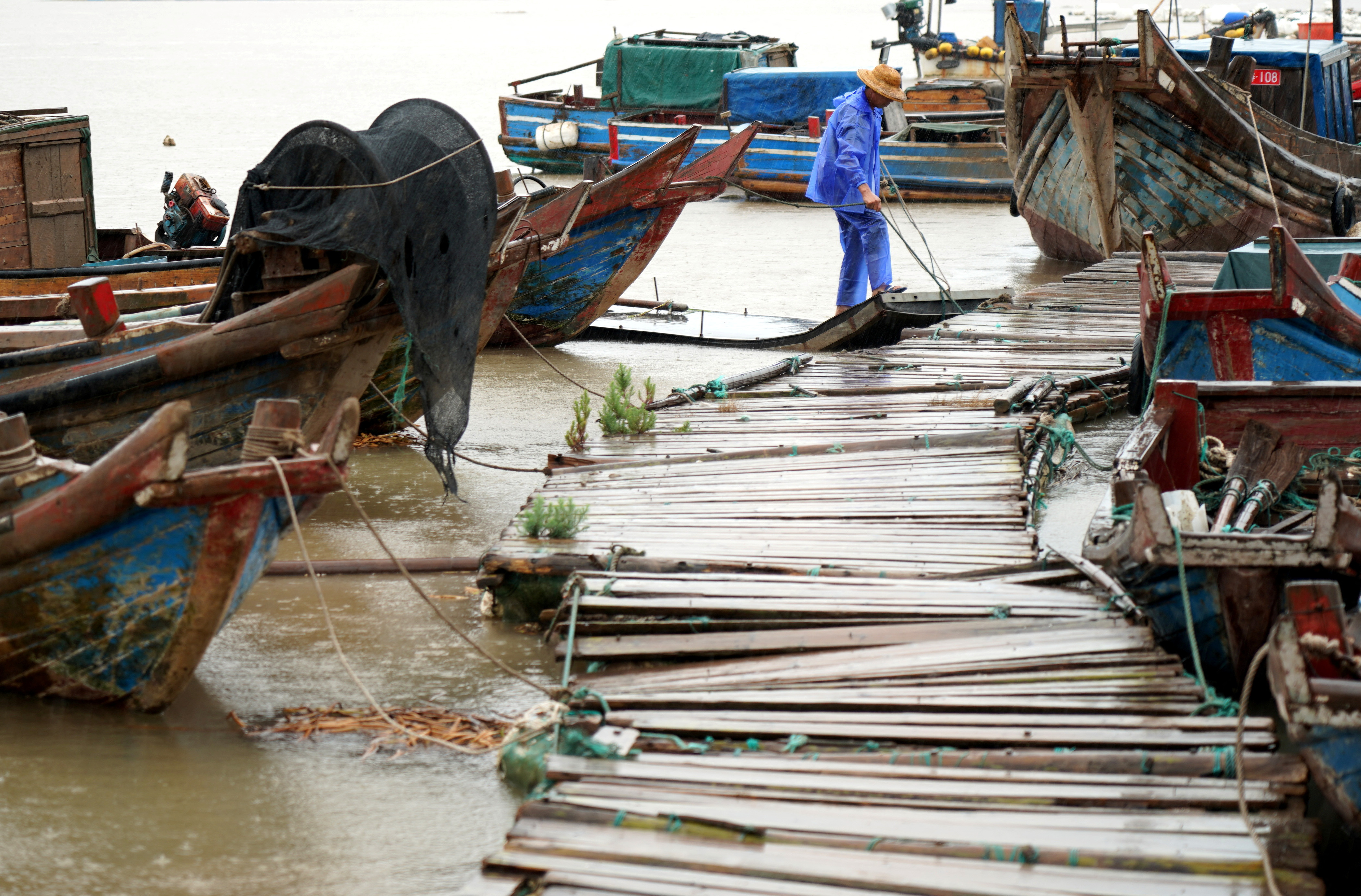 Man ties a boat to a pier as Typhoon Muifa approaches, at Yueqing bay in Wenzhou