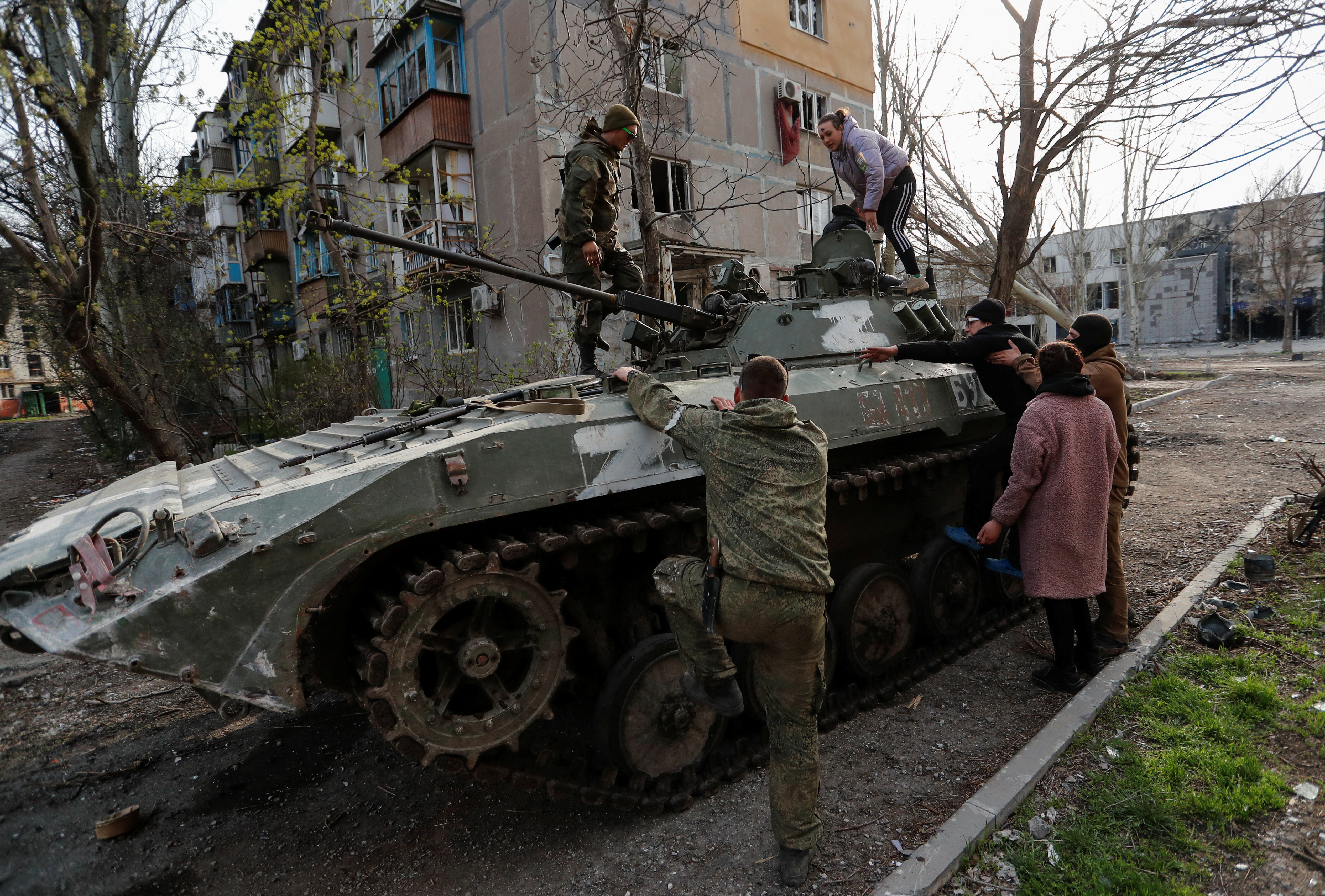 Service members of pro-Russian troops help civilians to get on an armoured vehicle in Mariupol