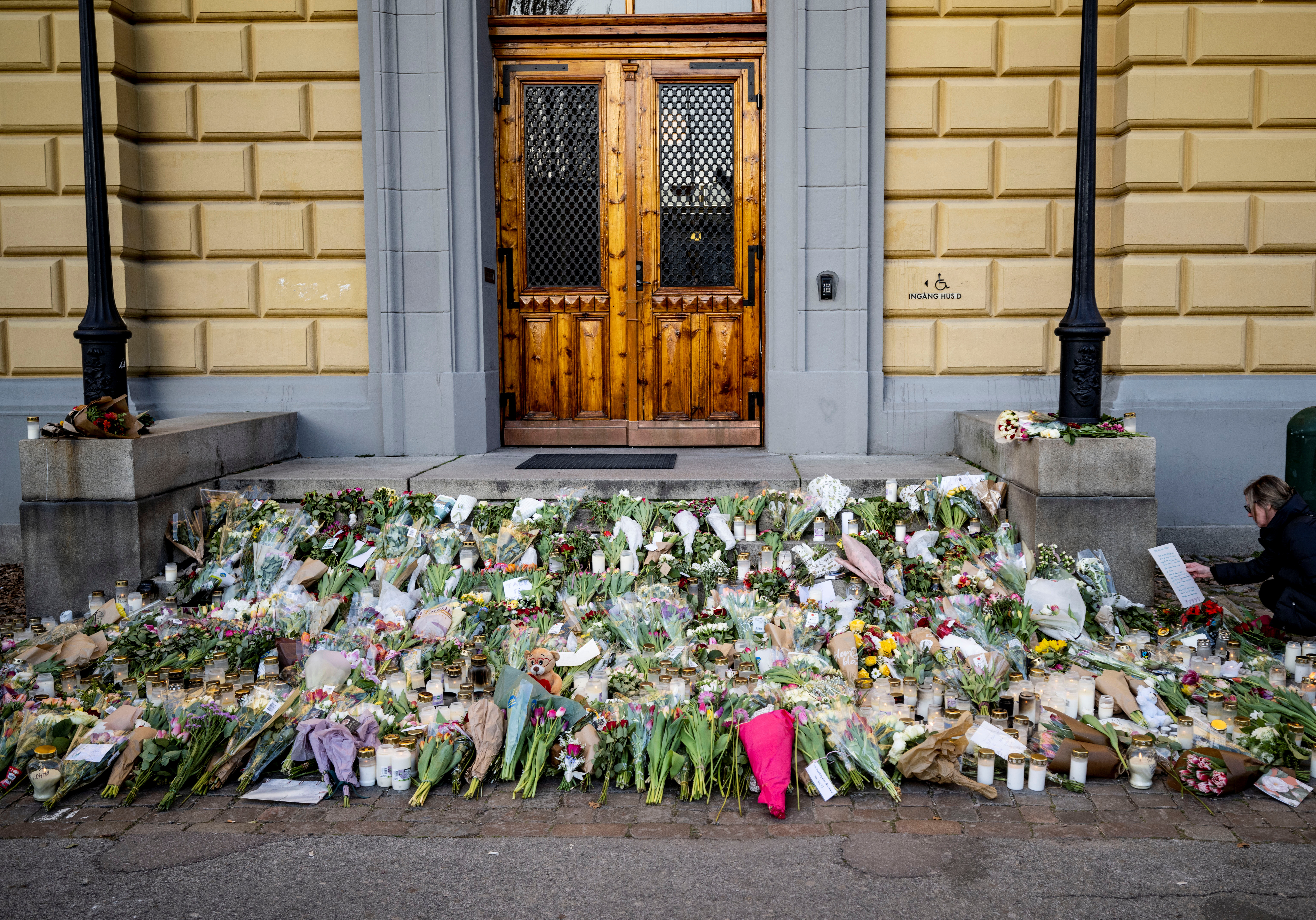 People lay flowers outside Malmo Latin School where two women were killed in Malmo