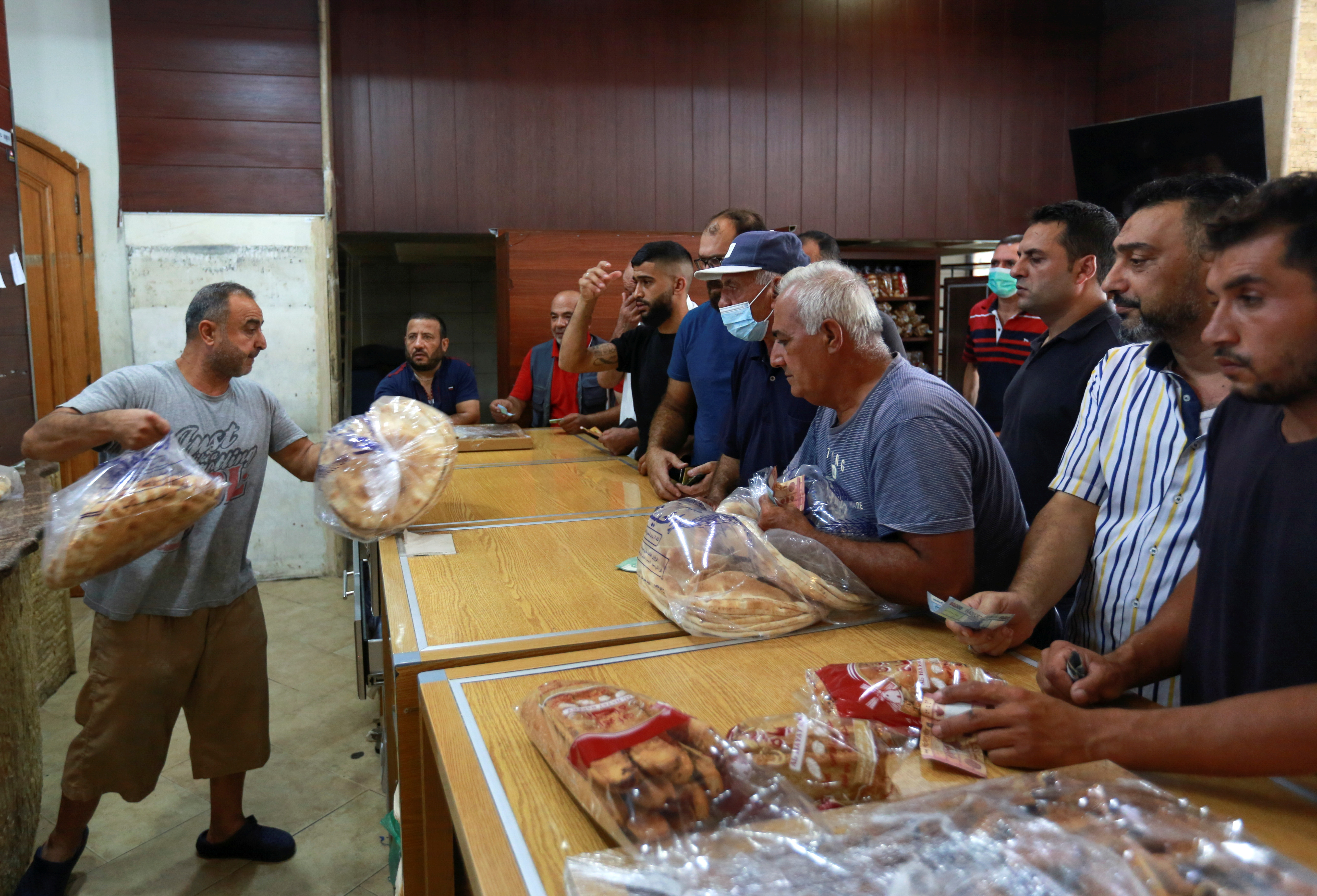 People queue to buy bread from a bakery in Sidon