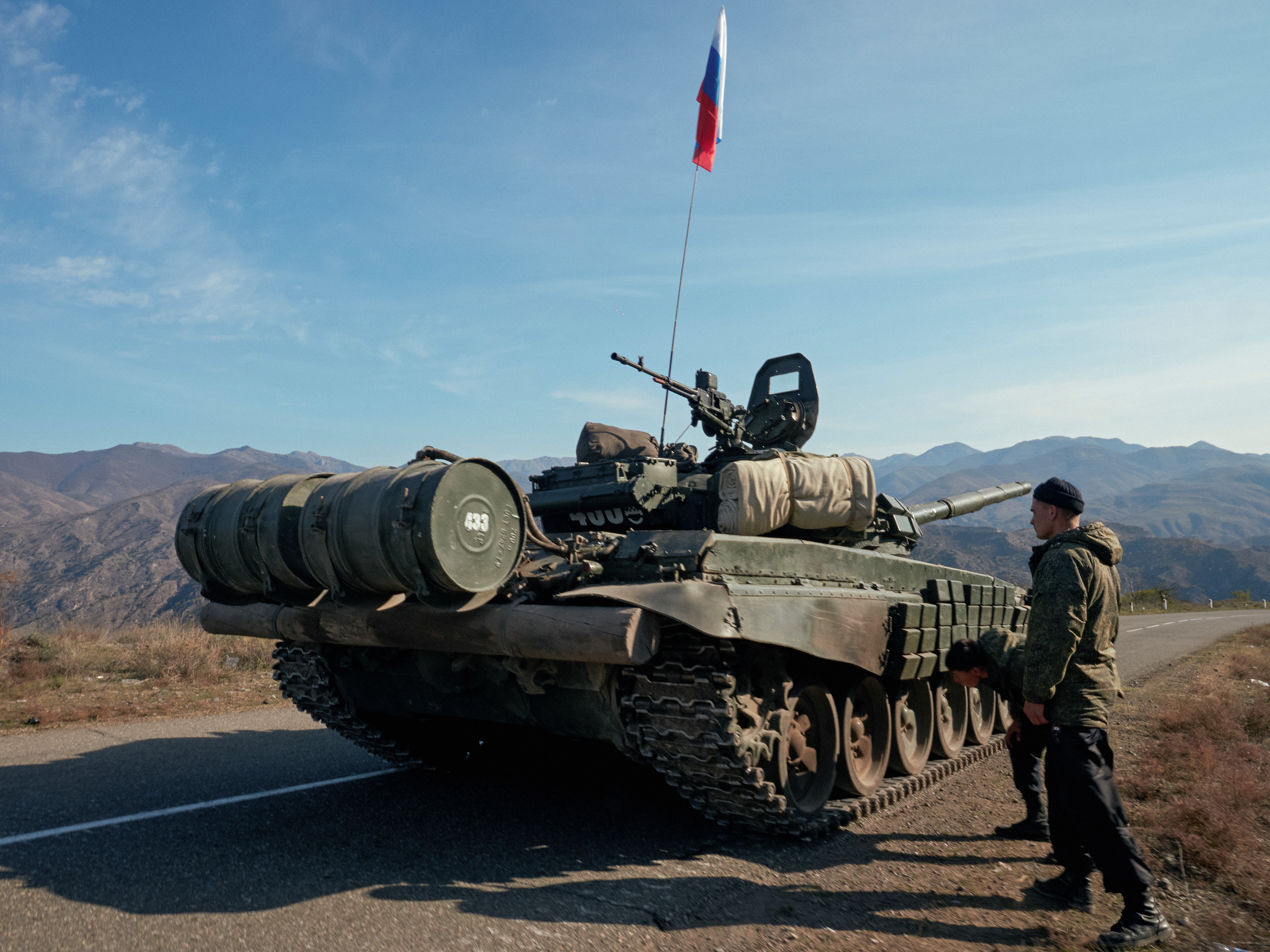Service members of the Russian peacekeeping troops stand next to a tank in Nagorno-Karabakh