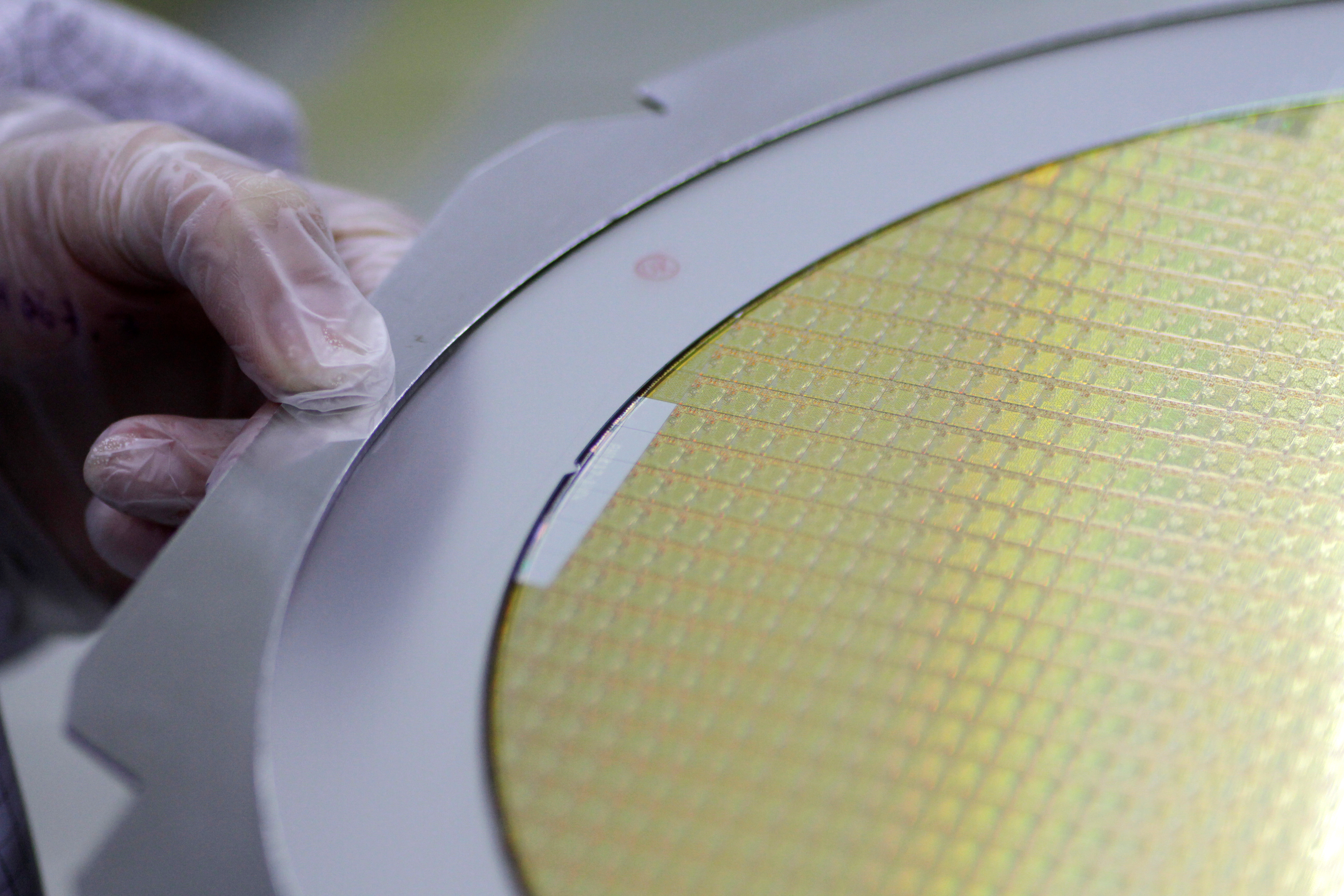 A worker checks a wafer chip in the clean room at the UTAC plant in Singapore