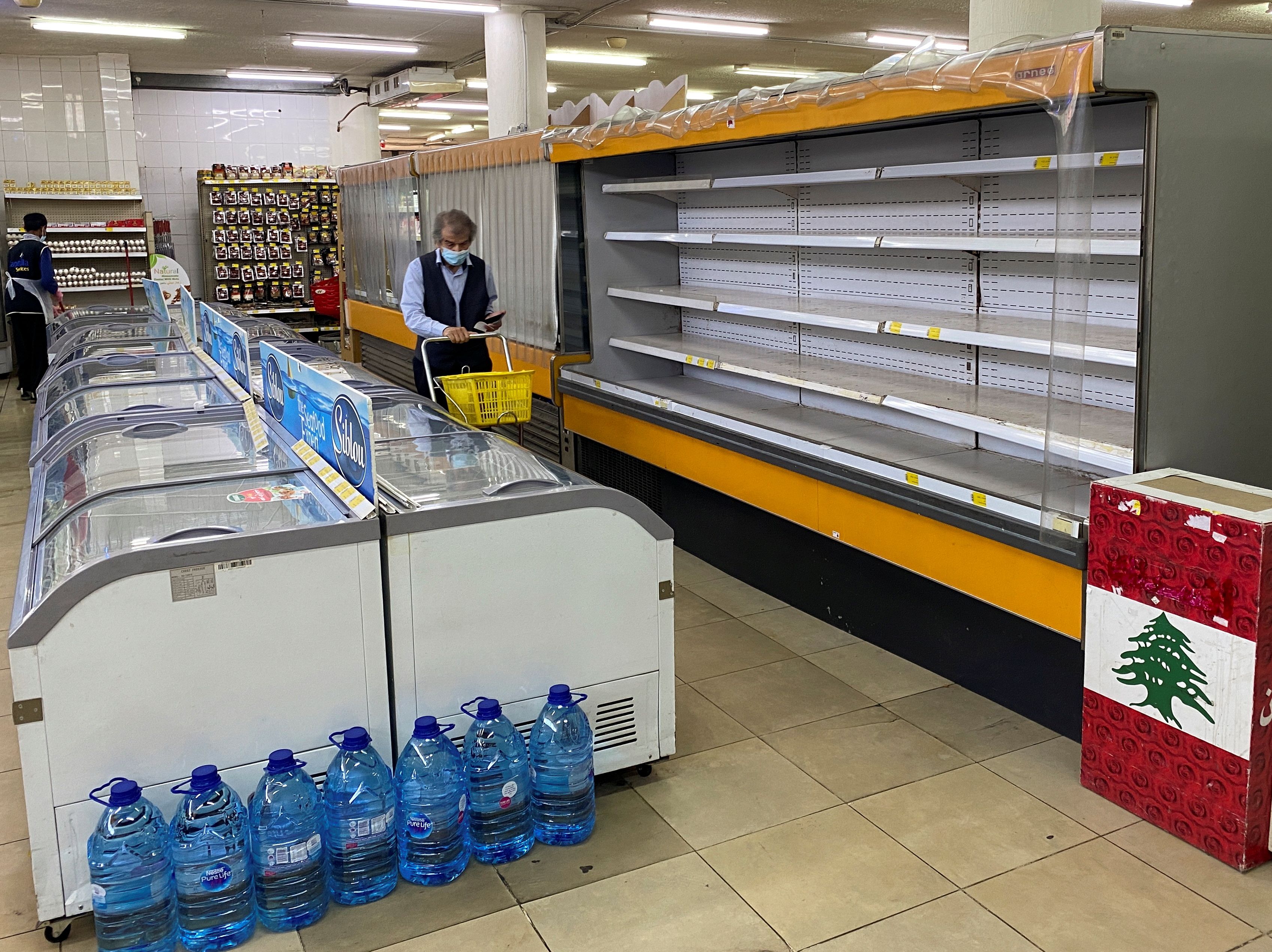 A shopper walks past an empty shelf at a supermarket in Hammana
