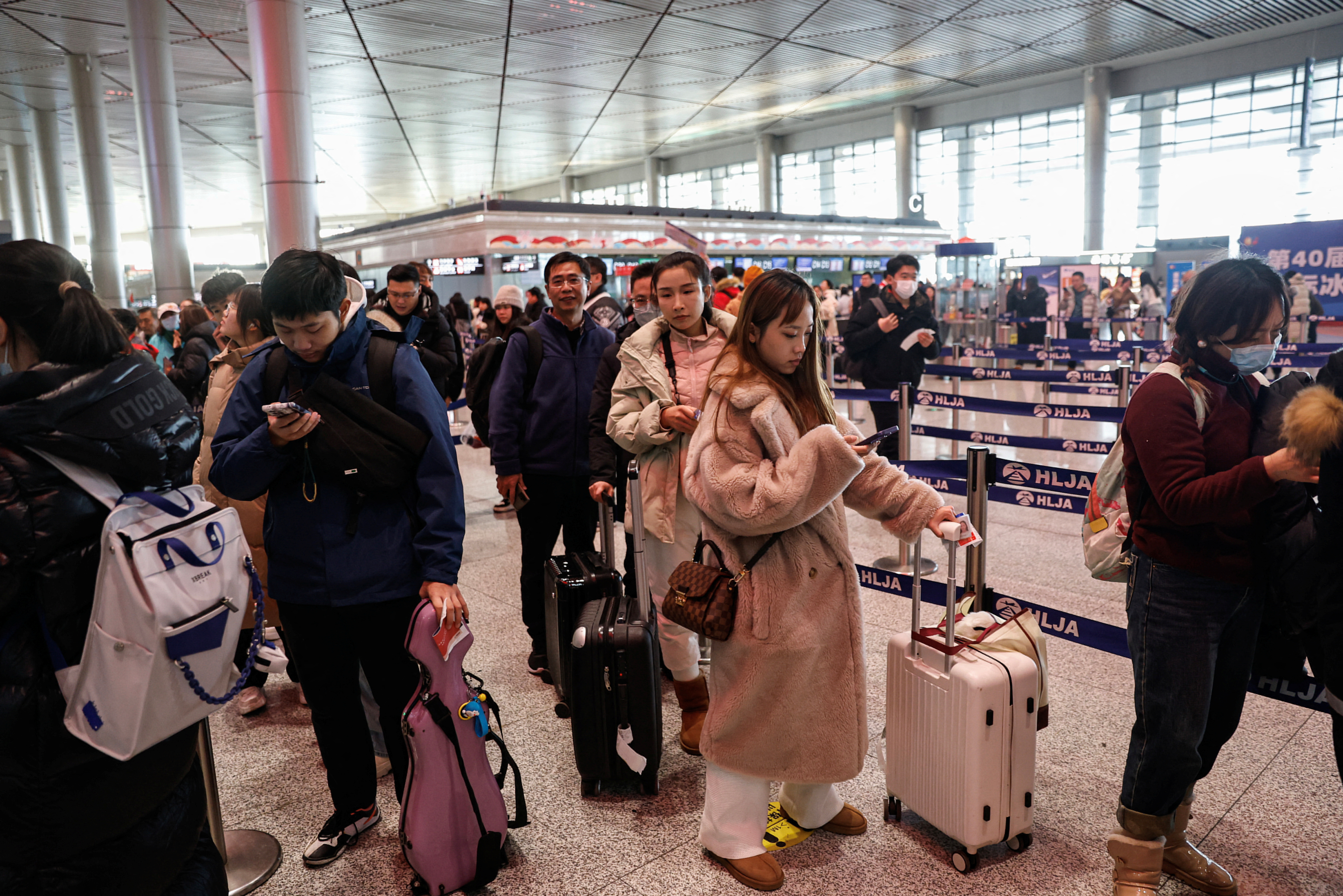 People wait in line to go through the security check at an airport in Harbin