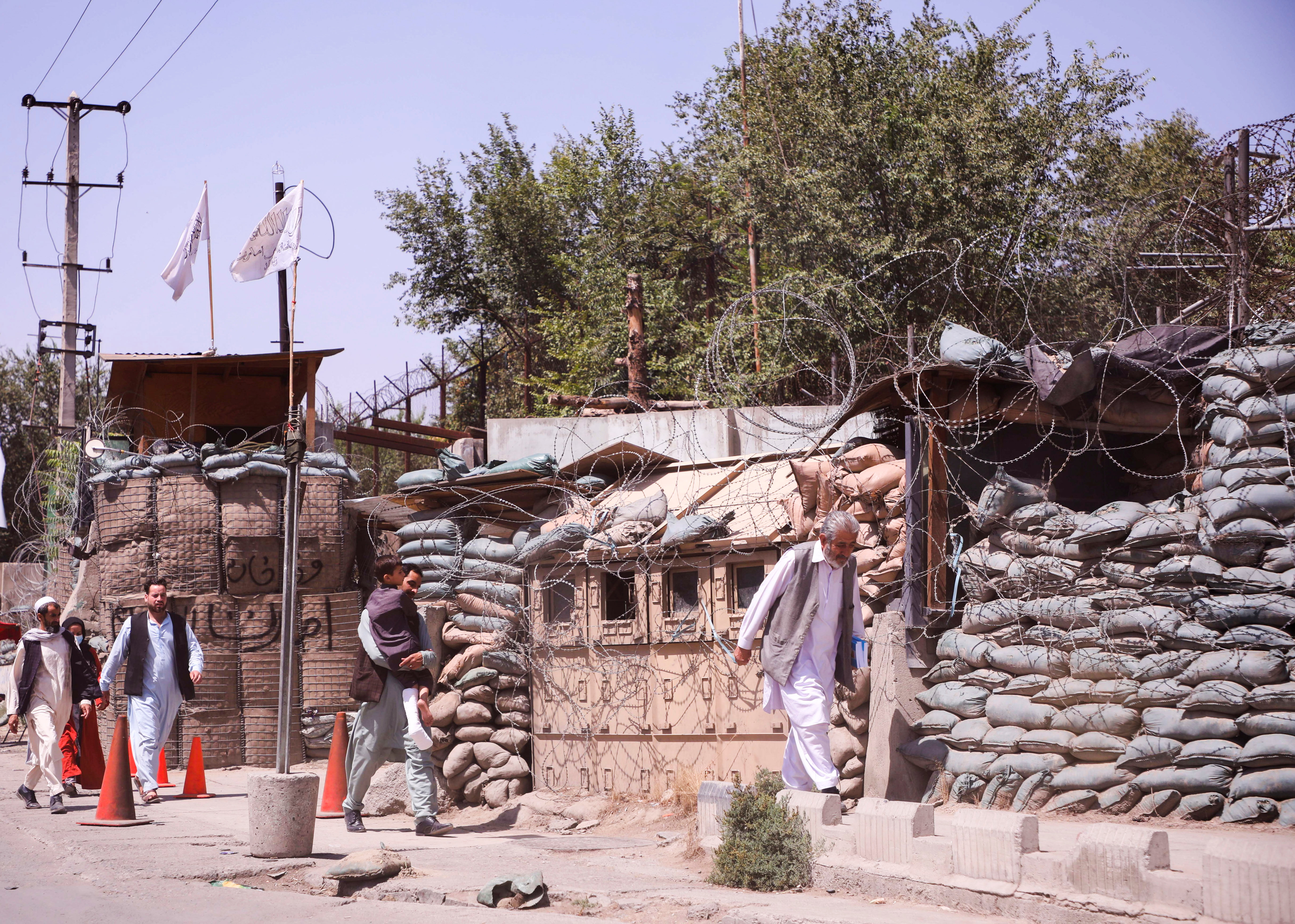 Afghan men walk past a military checkpoint in Kabul