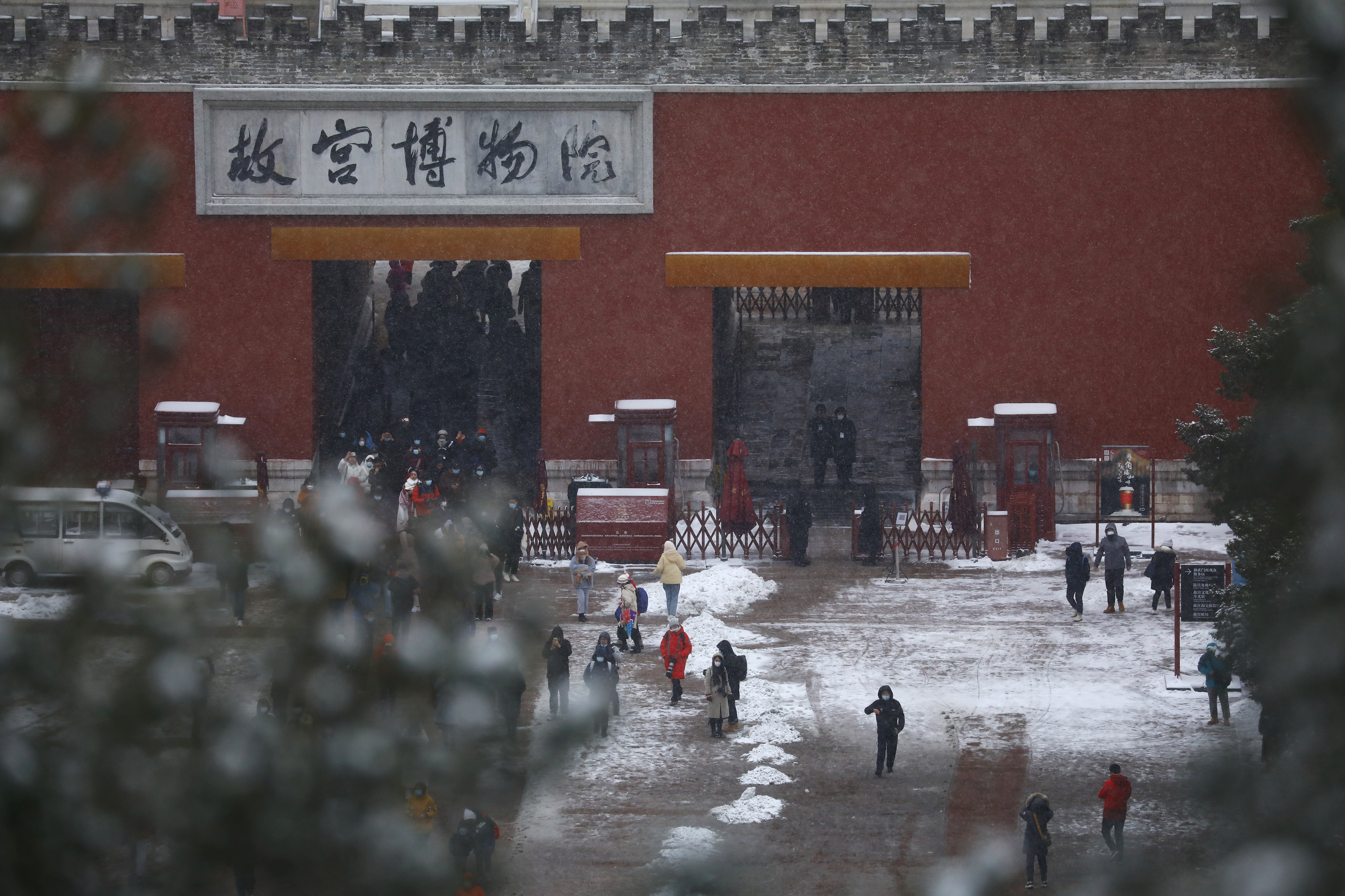 Tourists are seen at an entrance of the Forbidden City amid snowfall, in Beijing