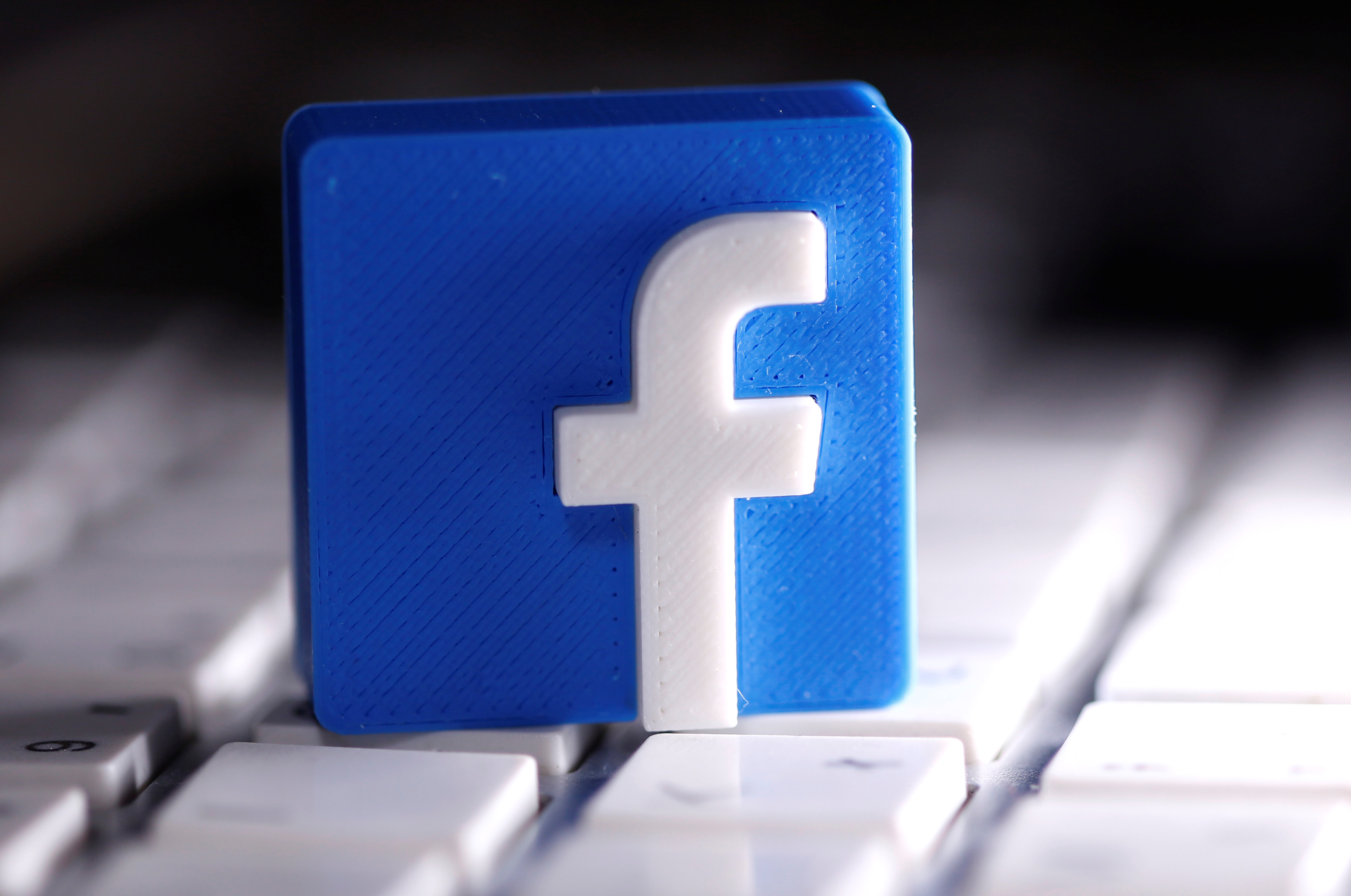 A 3D-printed Facebook logo is seen placed on a keyboard in this illustration