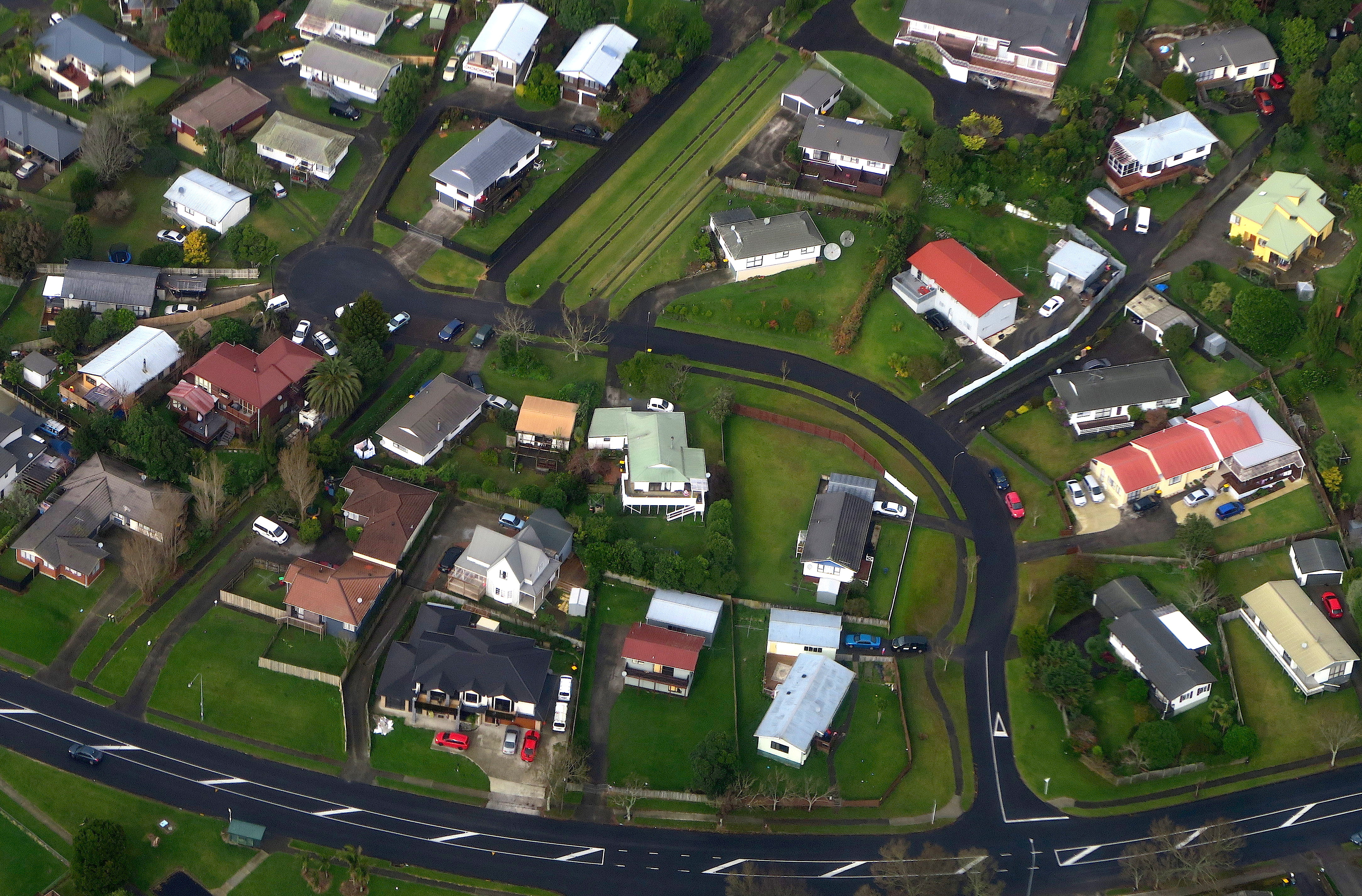Residential houses can be seen along a road in a suburb of Auckland in New Zealand