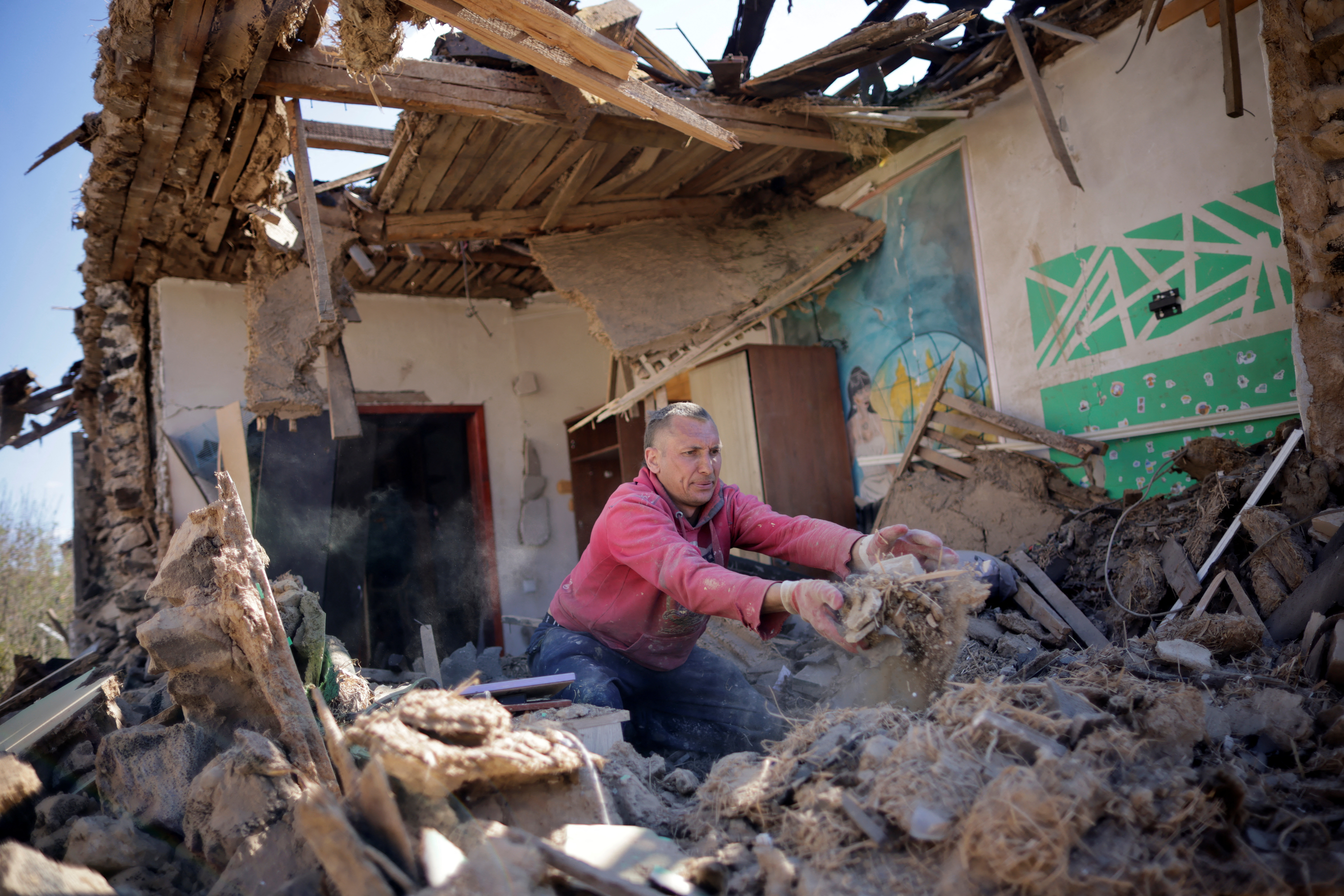 Un hombre ucraniano retira los escombros de su casa que fueron dañados por un ataque con misiles, mientras continúa la invasión de Rusia, en Zaporizhzhia
