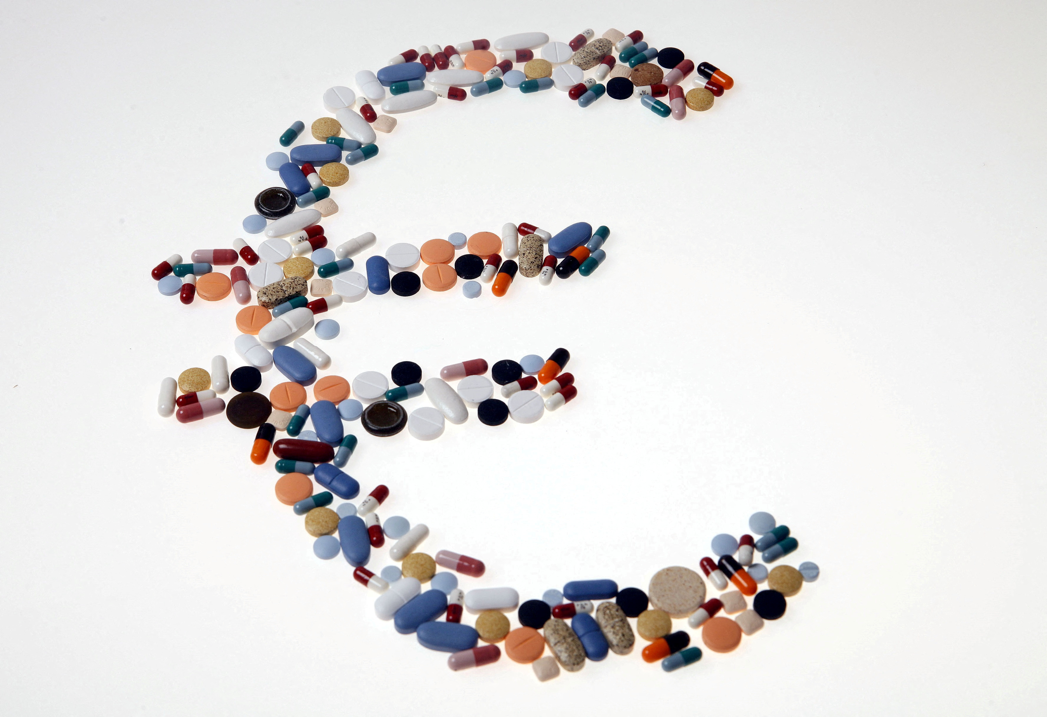 Pharmaceutical tablets and capsules are arranged on a table in this picture illustration