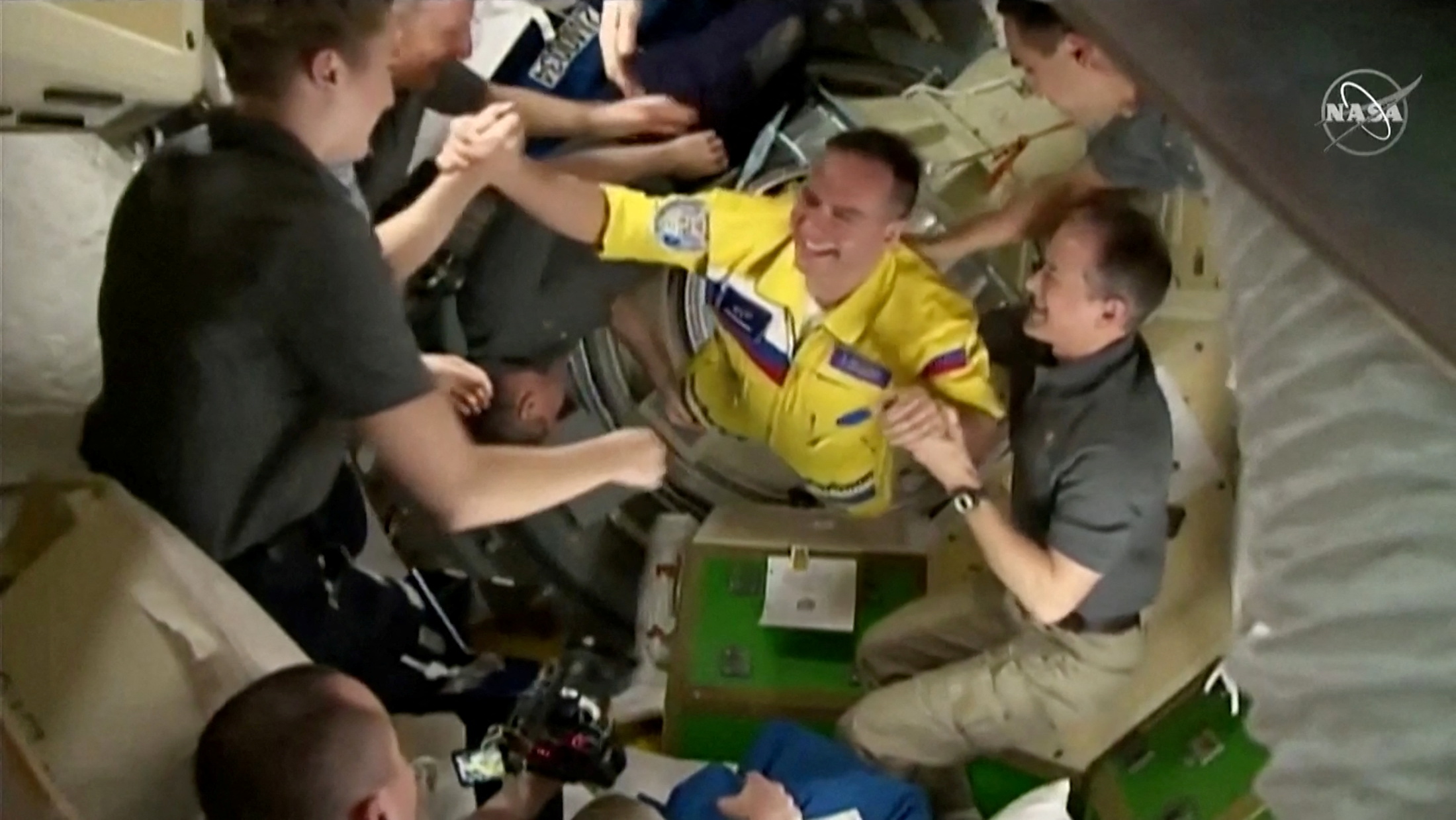 Russian cosmonauts arrive wearing yellow and blue flight suits at the International Space Station