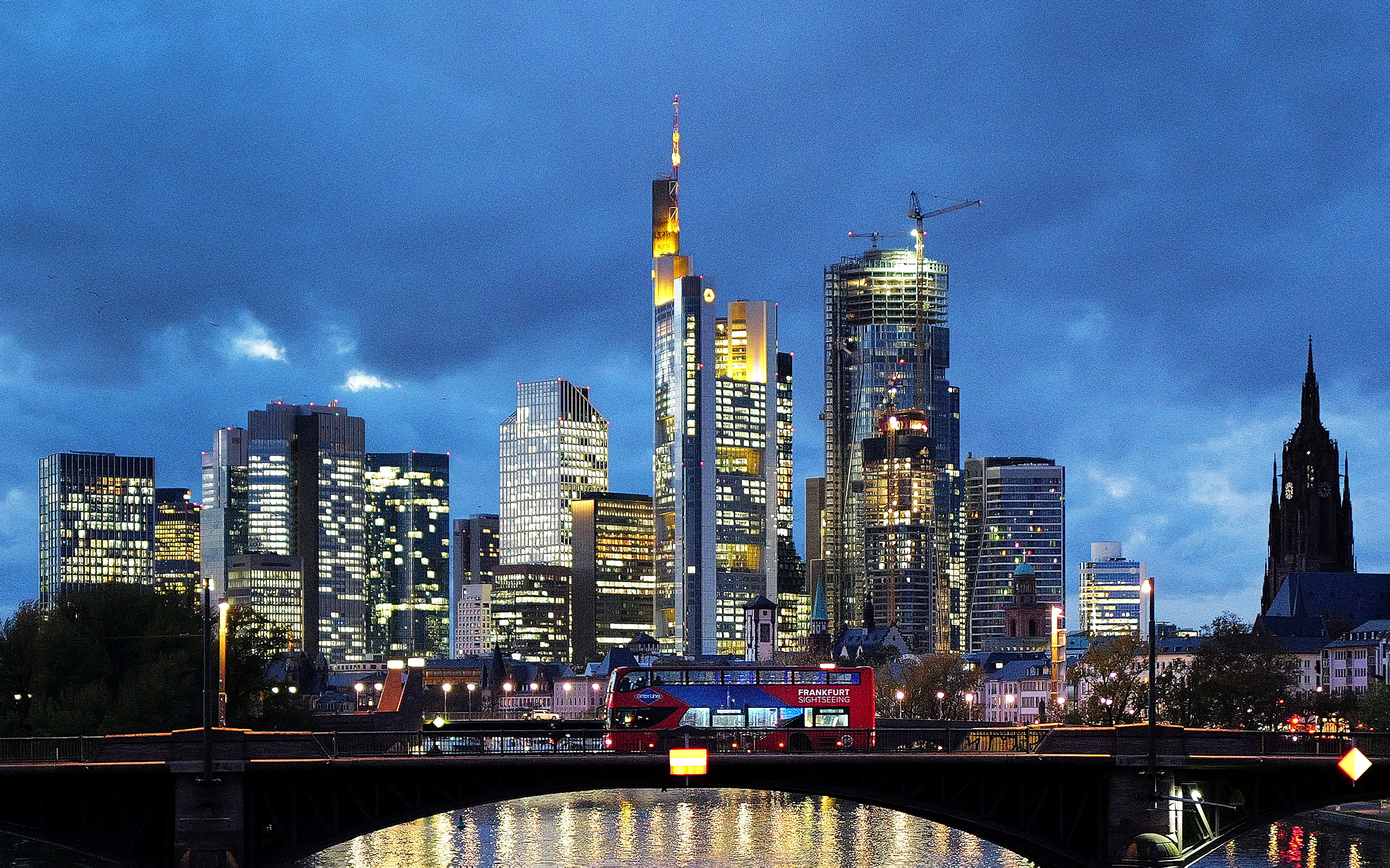 A double decker bus passes the skyline with its dominating banking district in Frankfurt