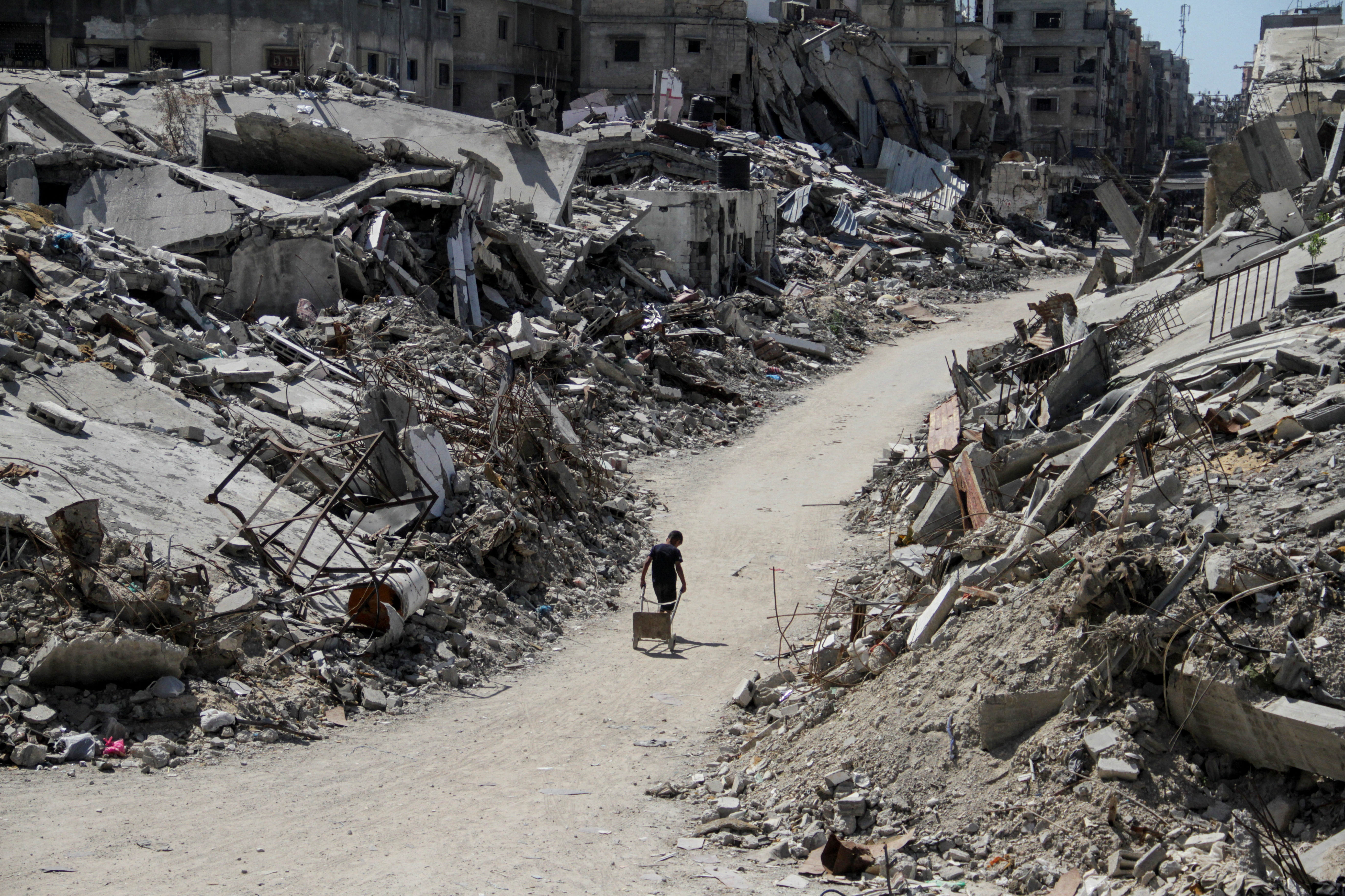 A Palestinian walks among the rubble of damaged buildings, in Beit Lahia