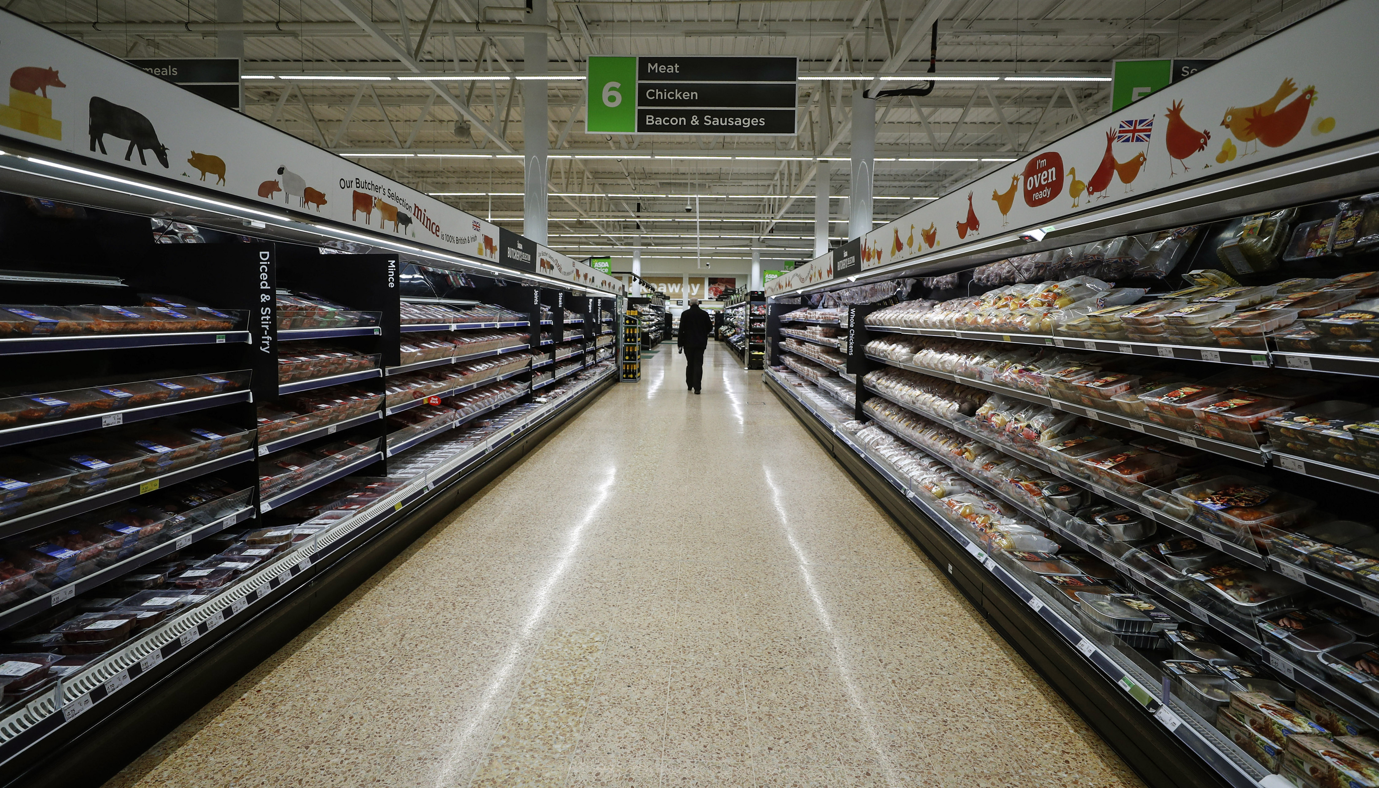 A shopper walks through the meat section at the Asda superstore in High Wycombe