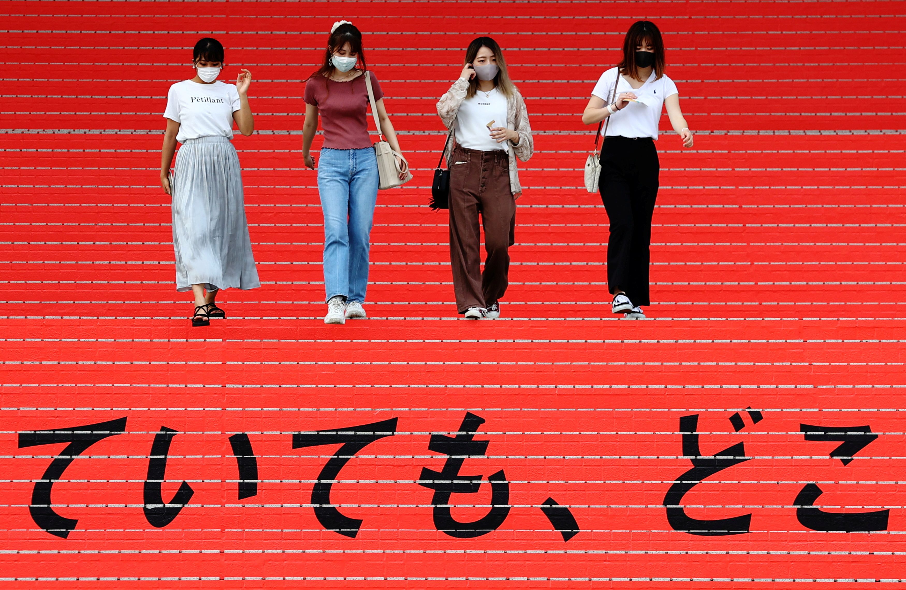 Women wearing protective masks, amid the coronavirus disease (COVID-19) outbreak, walk on a stair bearing a slogan cheering Japanese team during Tokyo 2020 Olympic Games in Tokyo, Japan, August 7, 2021. REUTERS/Kim Kyung-Hoon