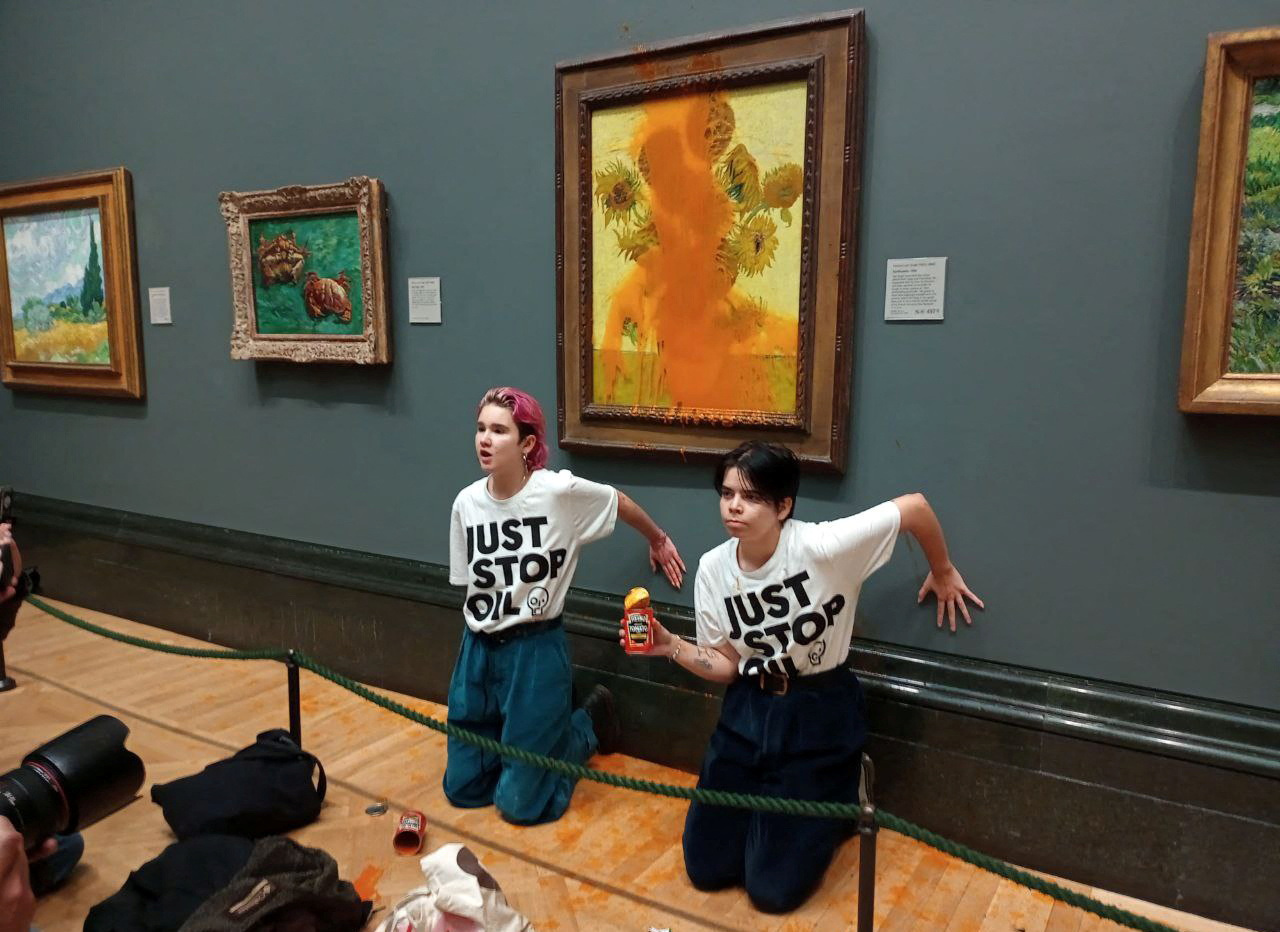 Activists of Just Stop Oil glue their hands to the wall after throwing soup at a van Gogh's painting Sunflowers at the National Gallery in London