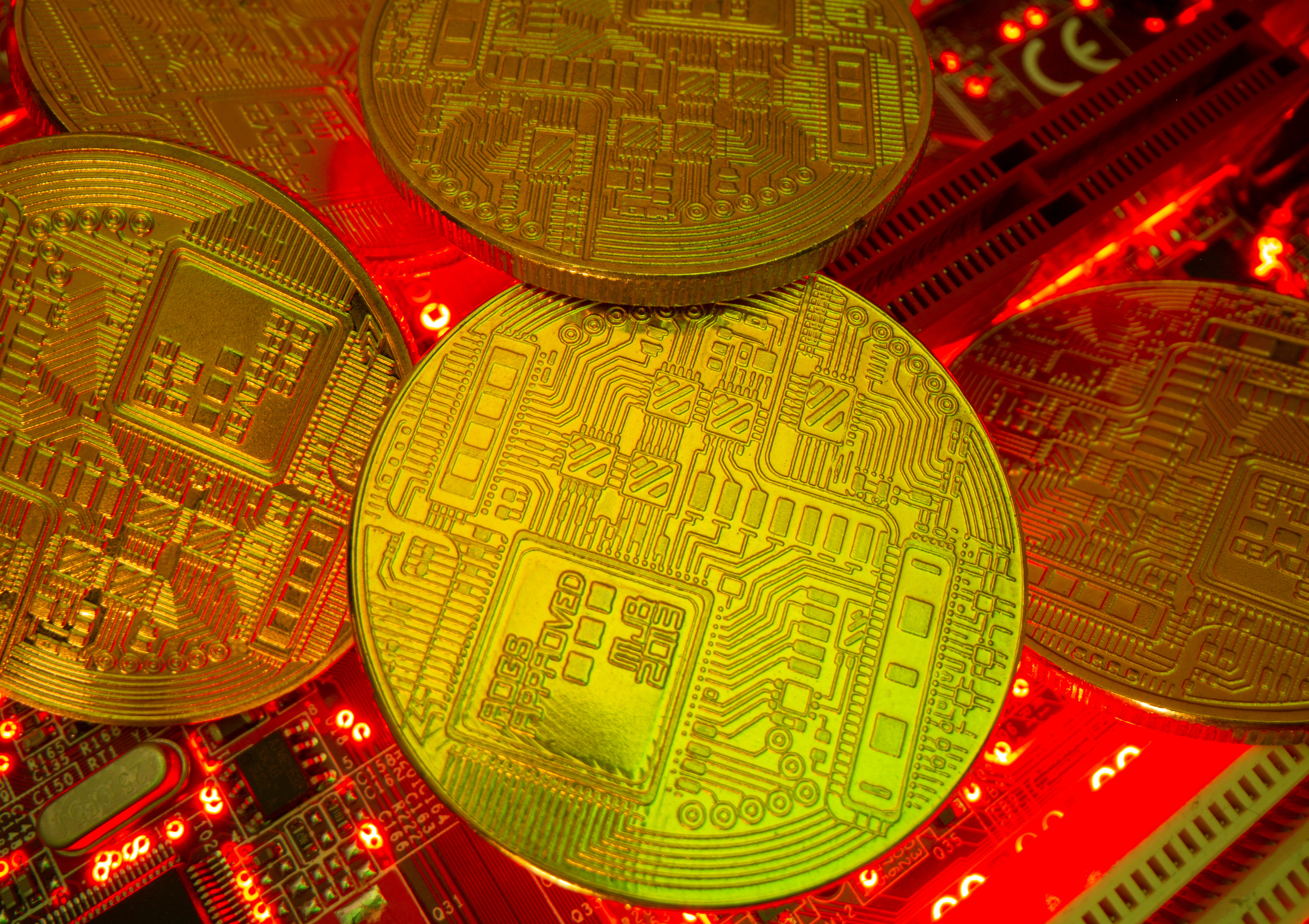 Representations of the virtual currency stand on a motherboard in this picture illustration
