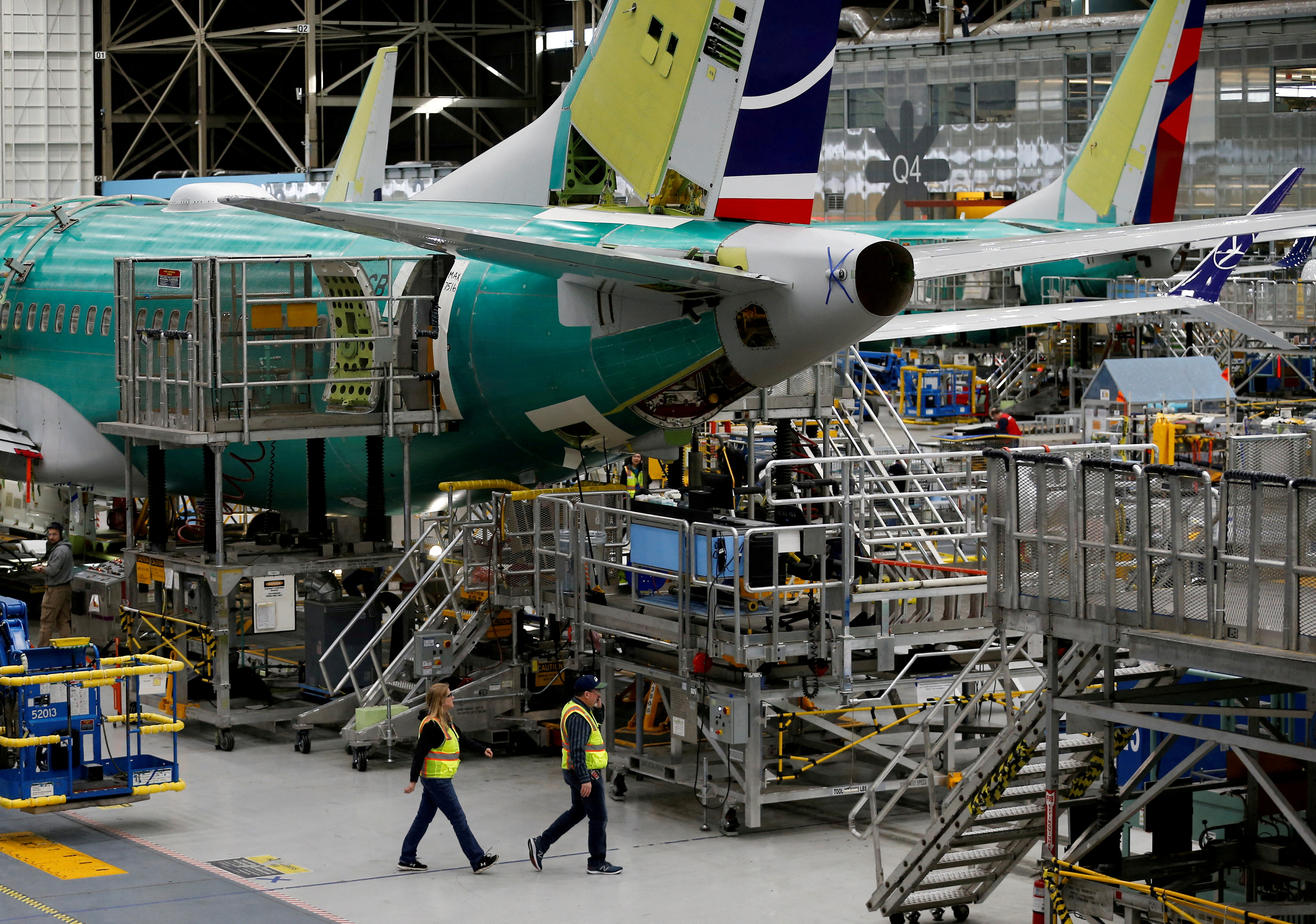 Employees walk by the end of a 737 Max aircraft at the Boeing factory in Renton