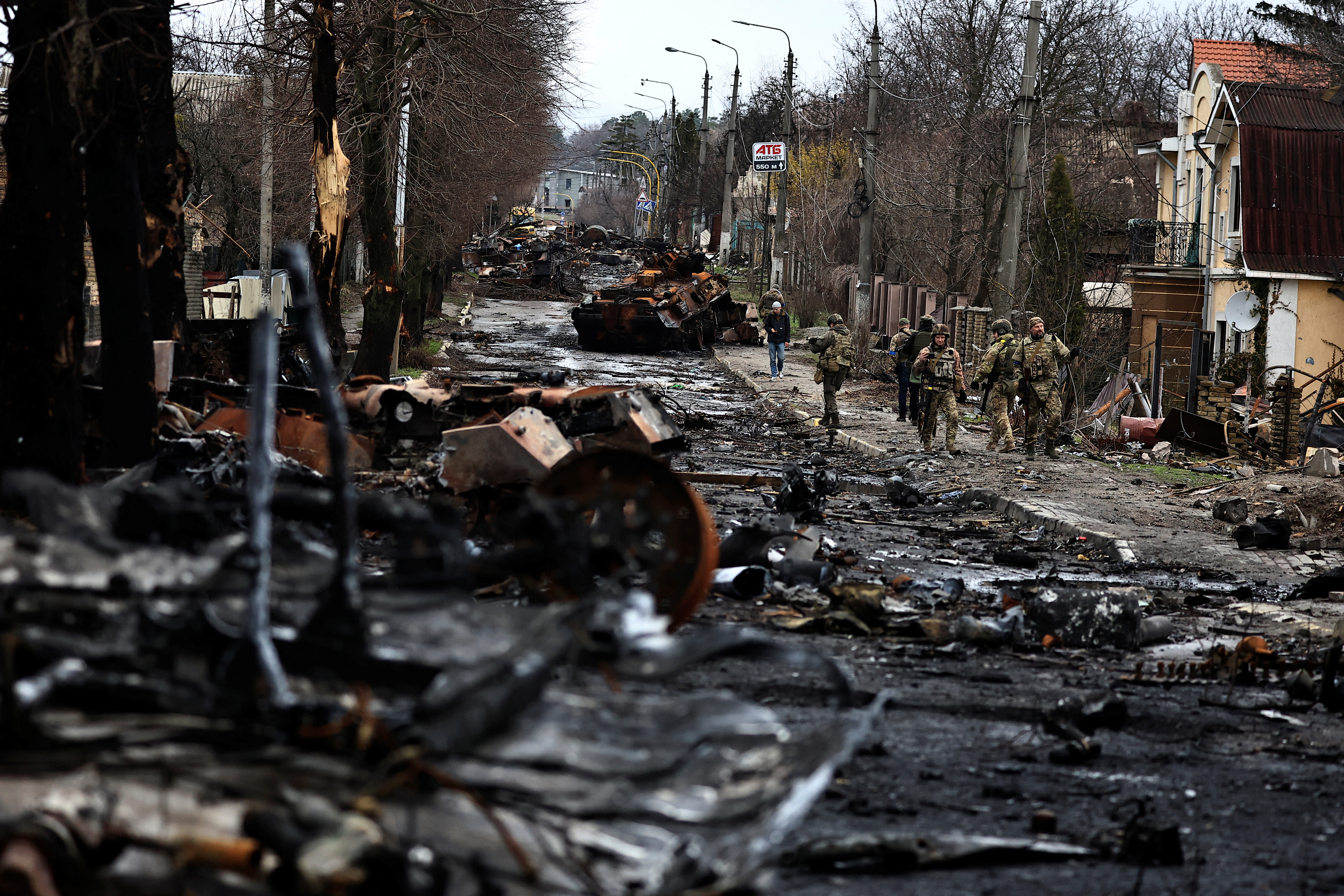 Soldiers walk past a destroyed Russian tank and armoured vehicles, amid Russia's invasion on Ukraine in Bucha, in Kyiv region