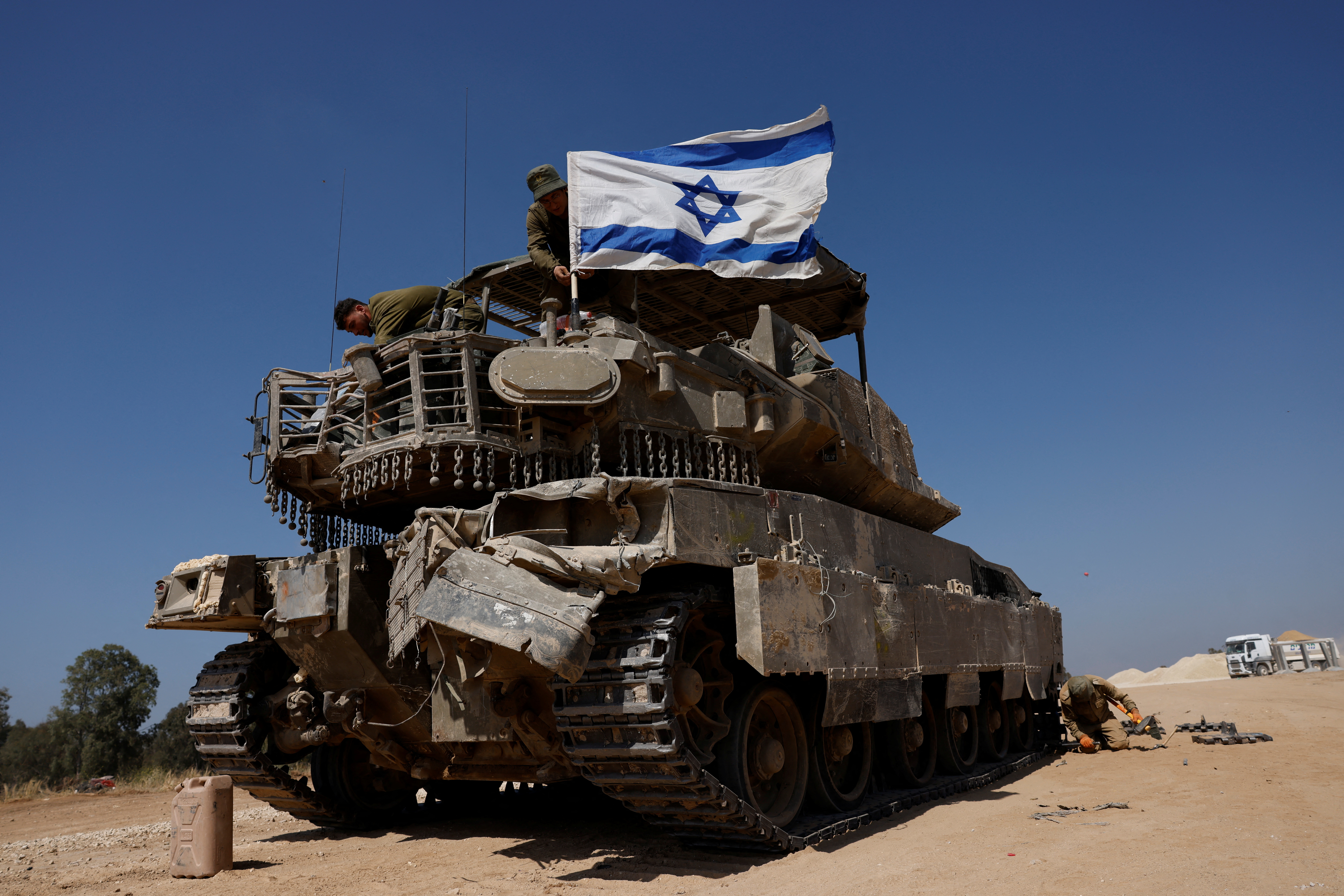 Israeli soldiers mount a flag on a military vehicle near the Israel-Gaza border
