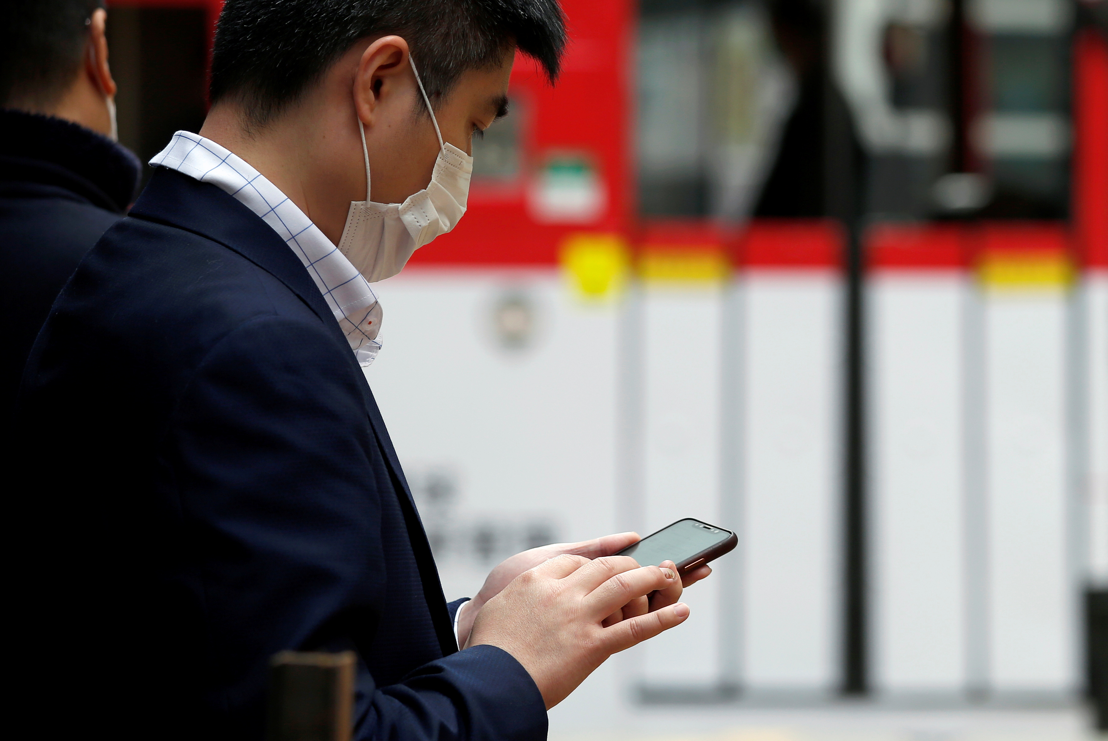 A man wears a protective mask as he looks at his mobile phone in Hong Kong