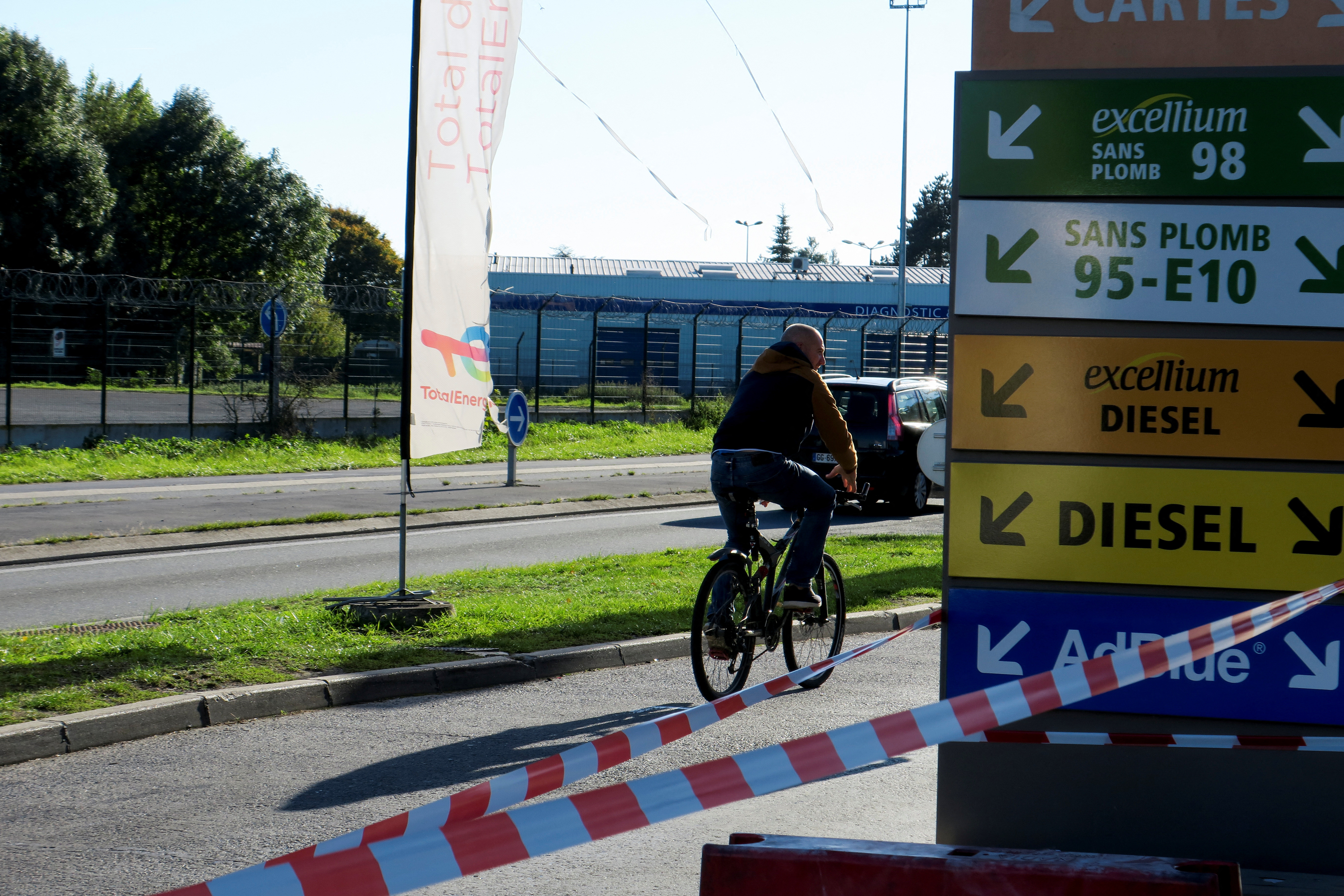 A cyclist rides past a closed TotalEnergies gas station near a petrol storage facility in Haulchin