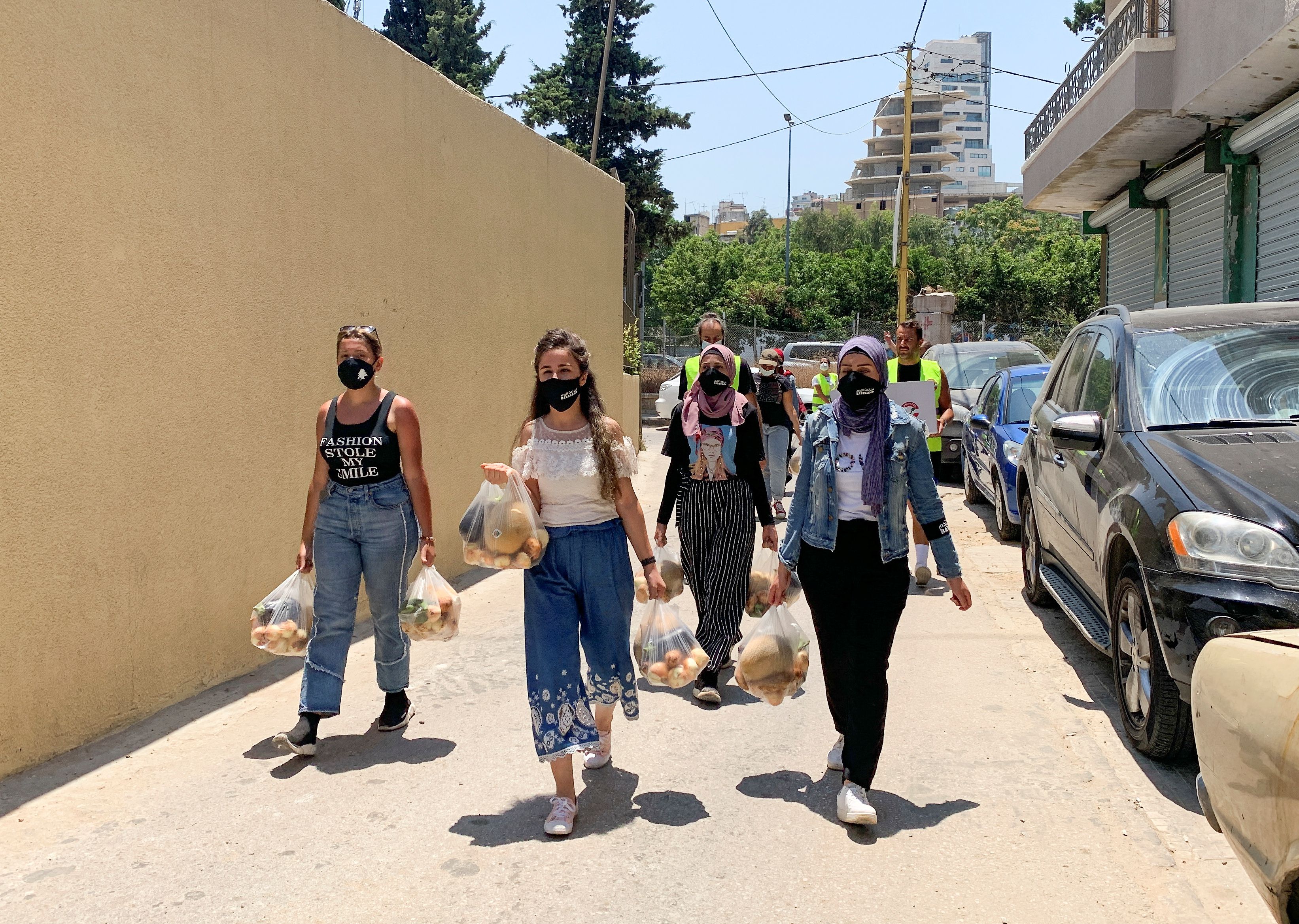 Volunteers from Base Camp, walk as they carry bags of vegetables to be distributed to people in need in Beirut