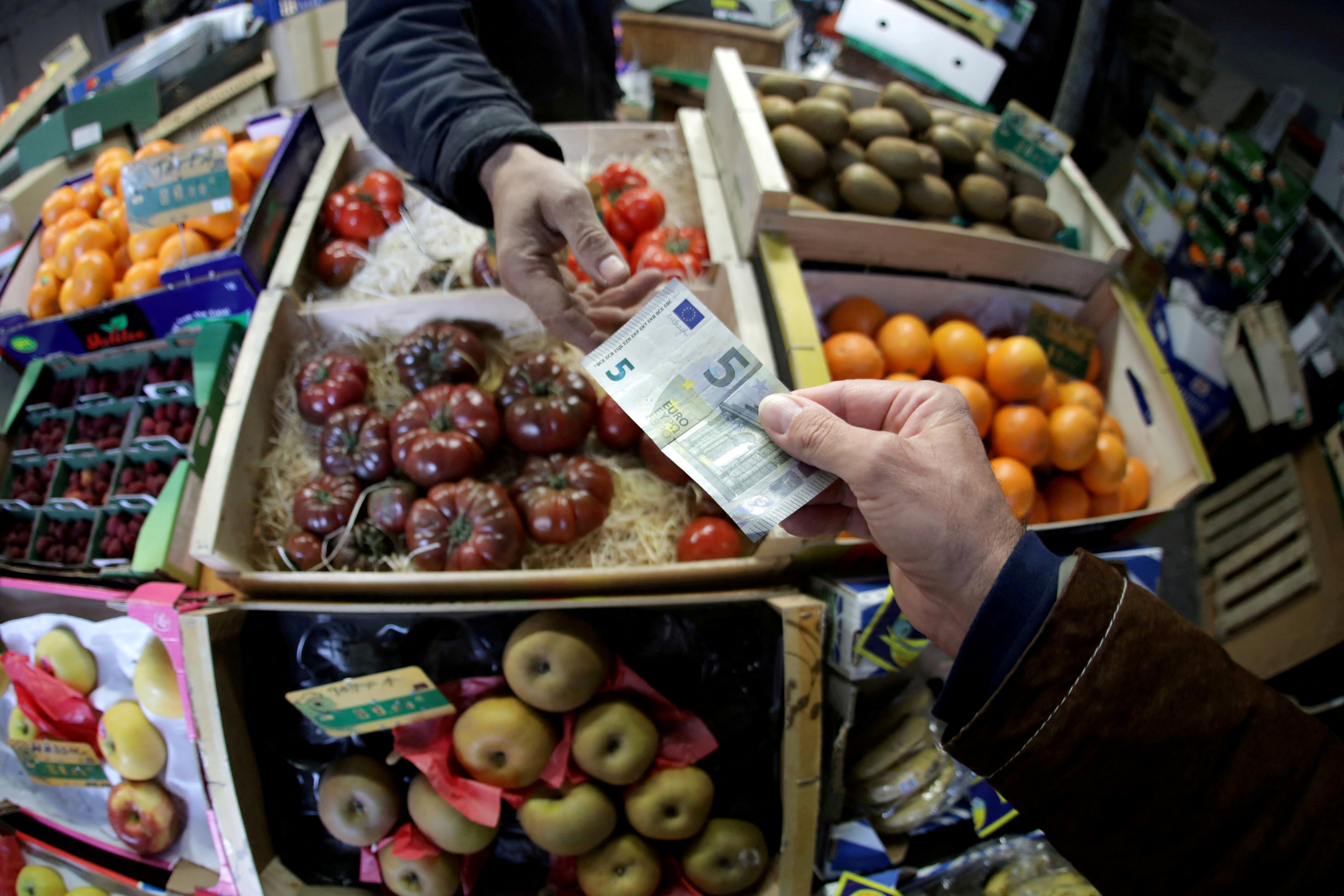A shopper pays with a Euro bank note in a market in Nice