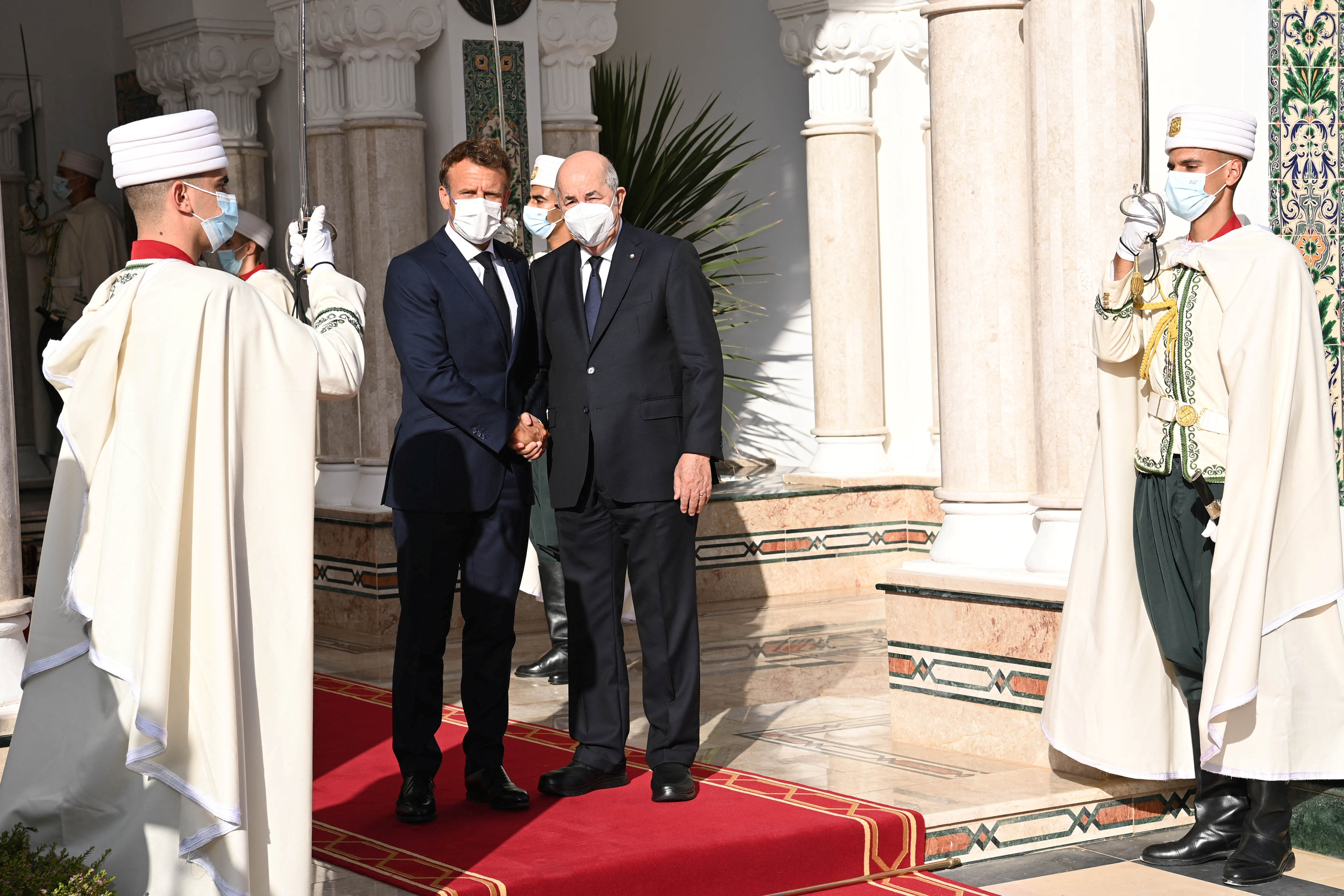 French President Emmanuel Macron shakes hand with Algerian President Abdelmadjid Tebboune at the presidential palace in Algiers