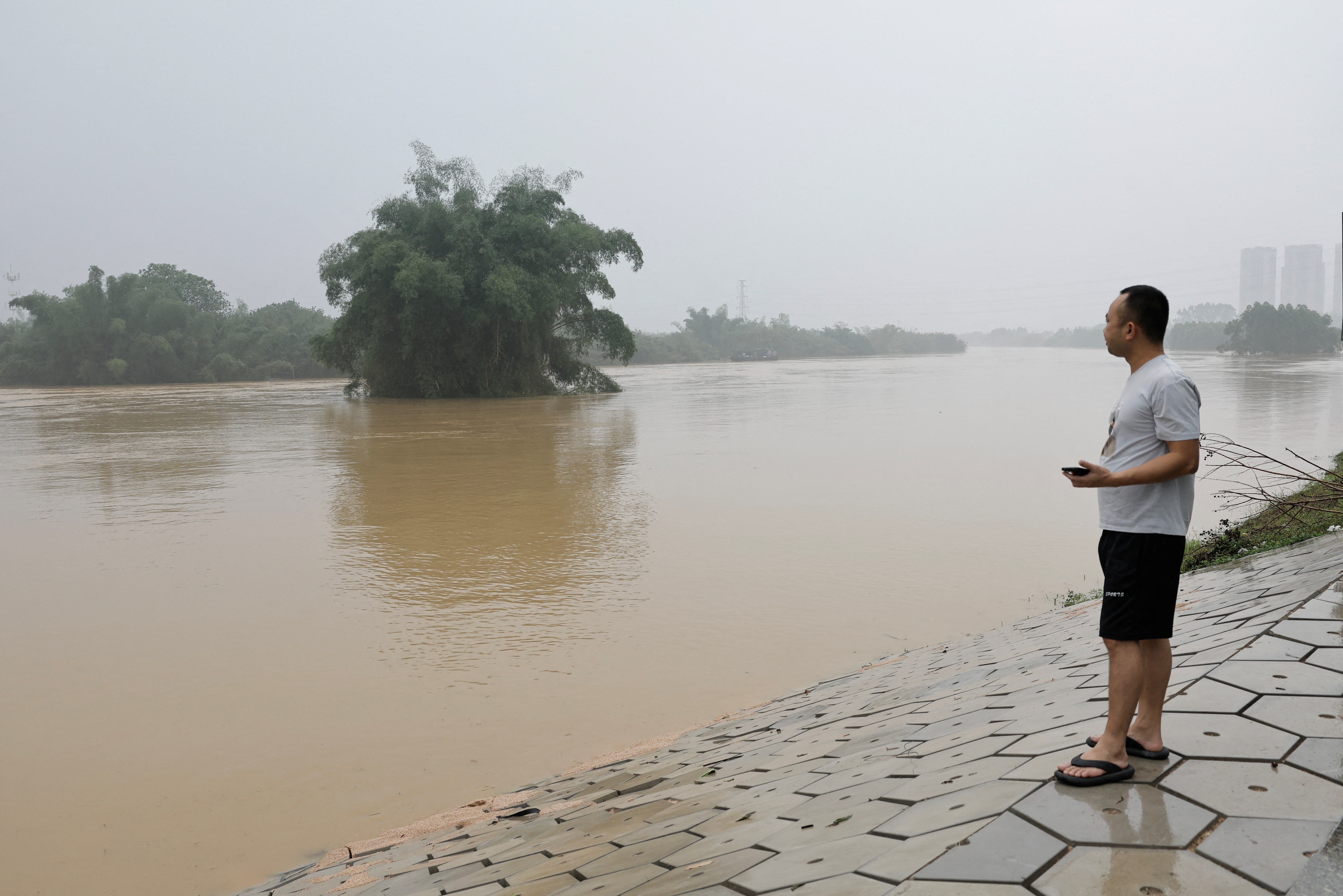Resident looks on as he stands near a flooded river following heavy rainfall in Qingyuan, Guangdong