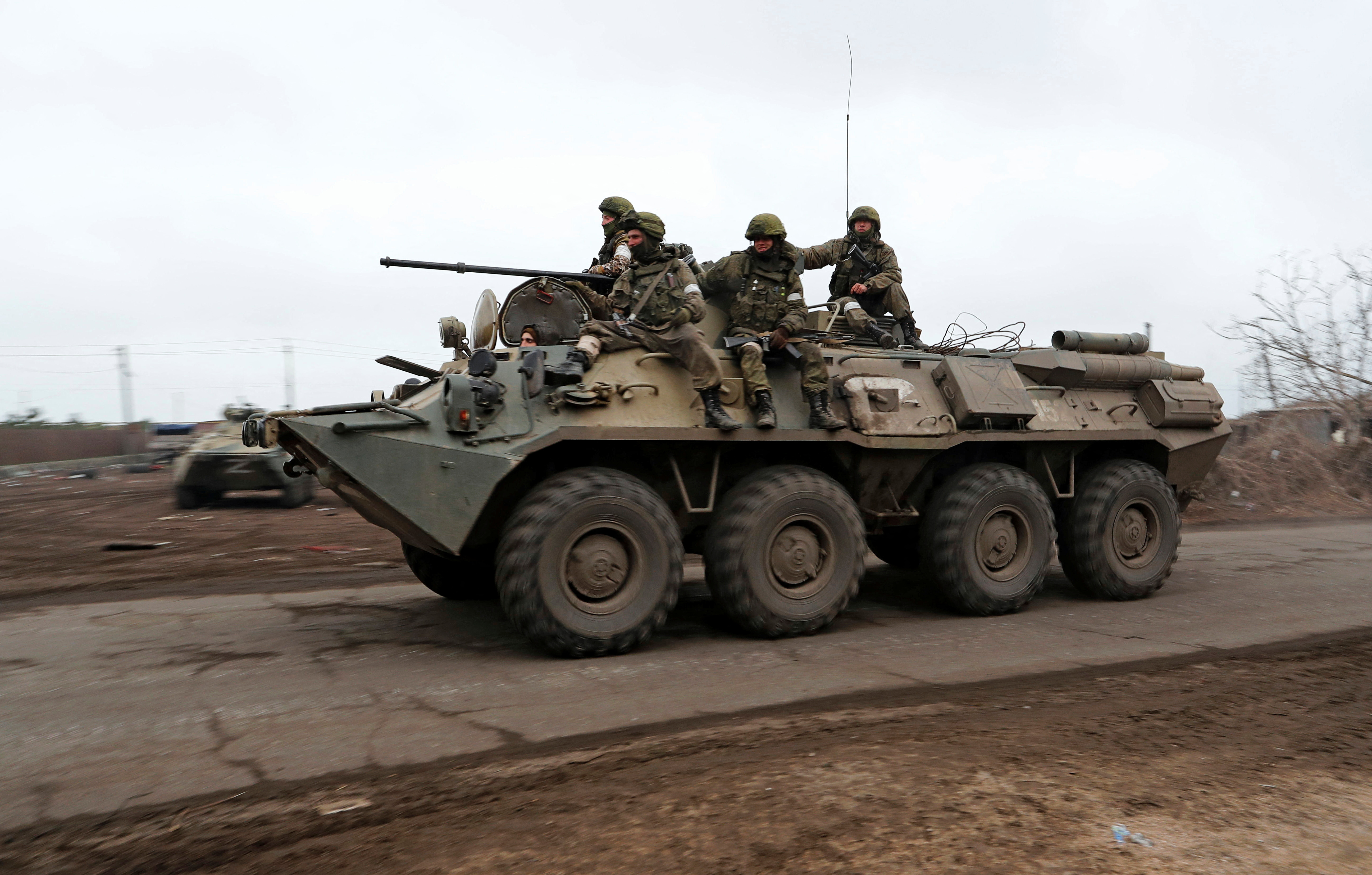 Service members of pro-Russian troops ride an armoured vehicle in Mariupol