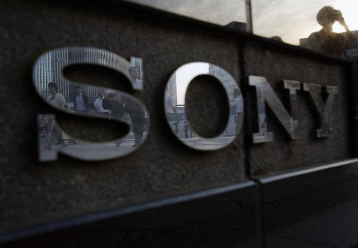 Pedestrians are reflected in a logo of Sony Corp outside its showroom in Tokyo