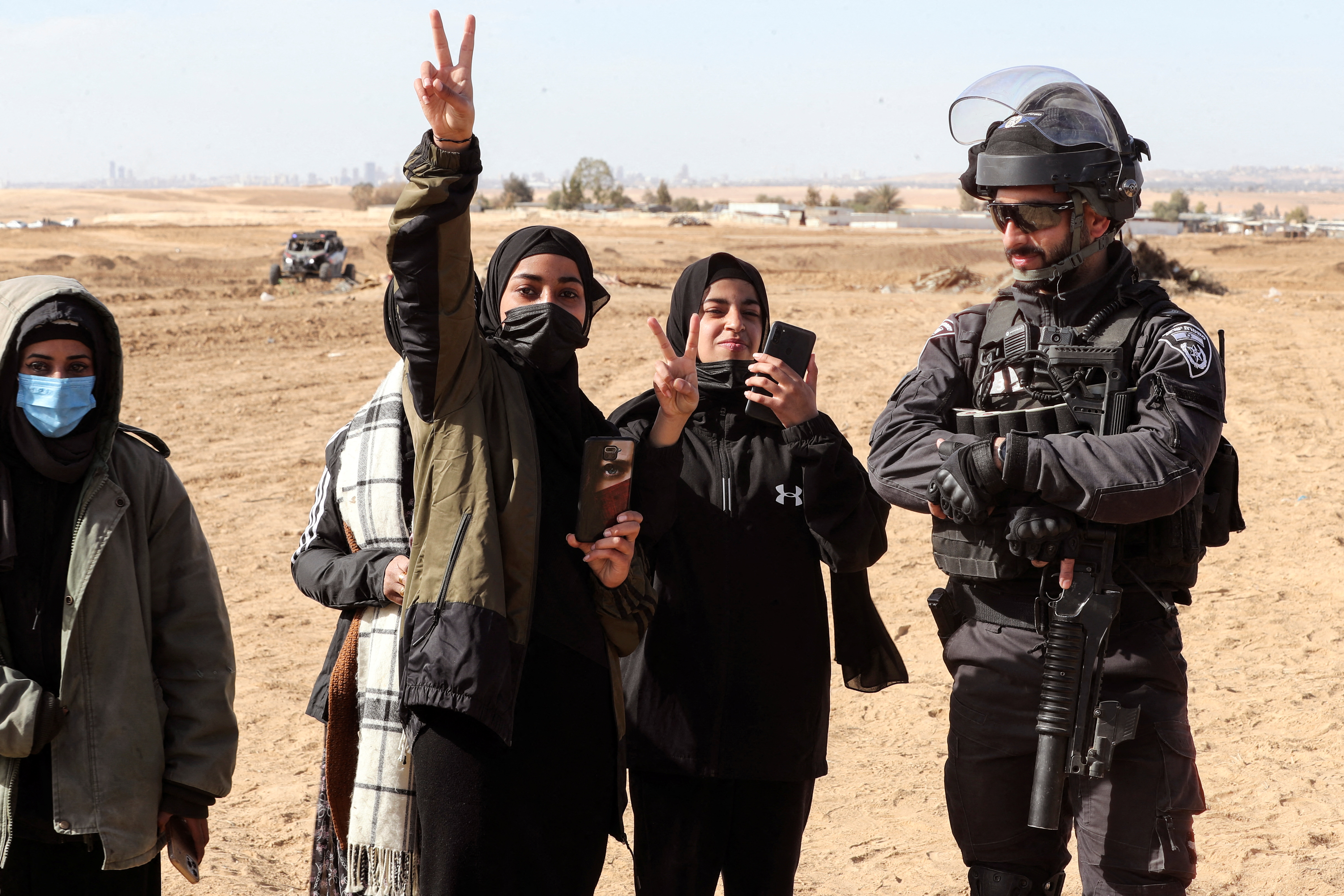 Bedouin women gesture as they stand by an Israeli policeman during a protest against forestation at the Negev desert village of Sawe al-Atrash, southern Israel