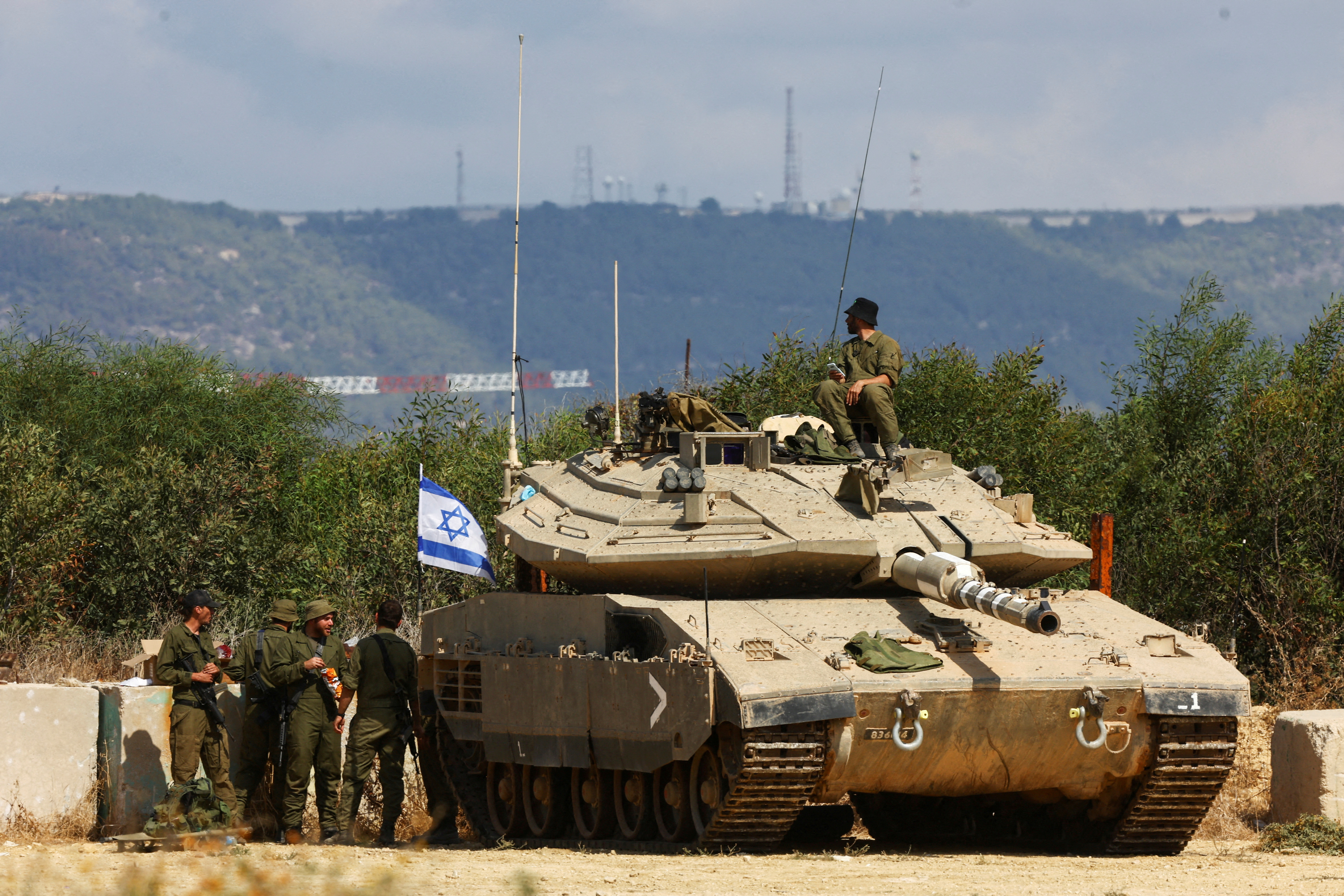 Israeli soldiers stand near to a tank near Israel's border with Lebanon in northern Israel