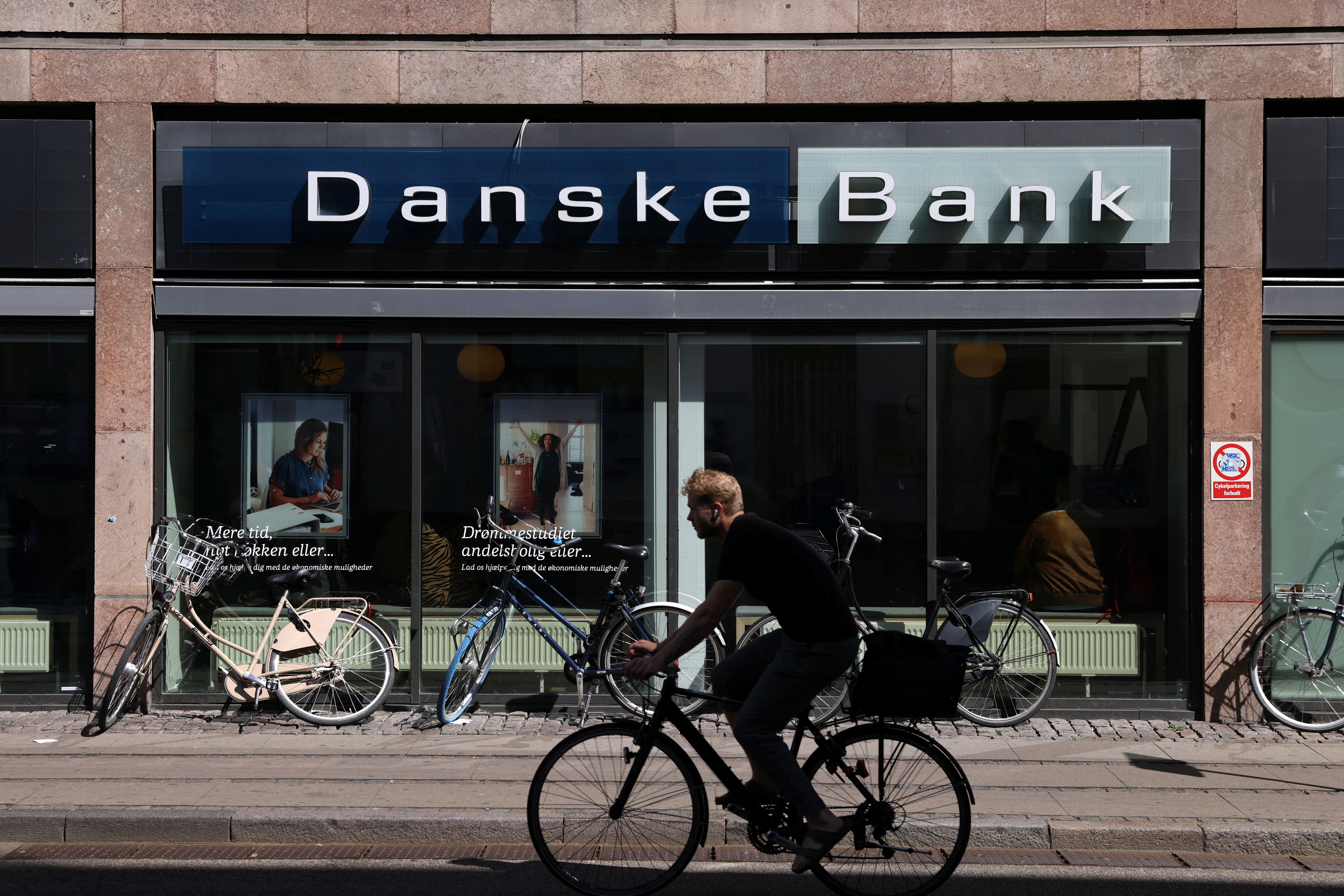 A person rides a bicycle past a Danske Bank branch in Copenhagen