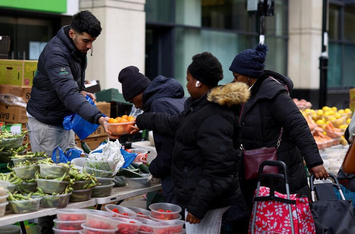 Customers buy fresh produce from a fruit and vegetable stall on Surrey Street market in Croydon