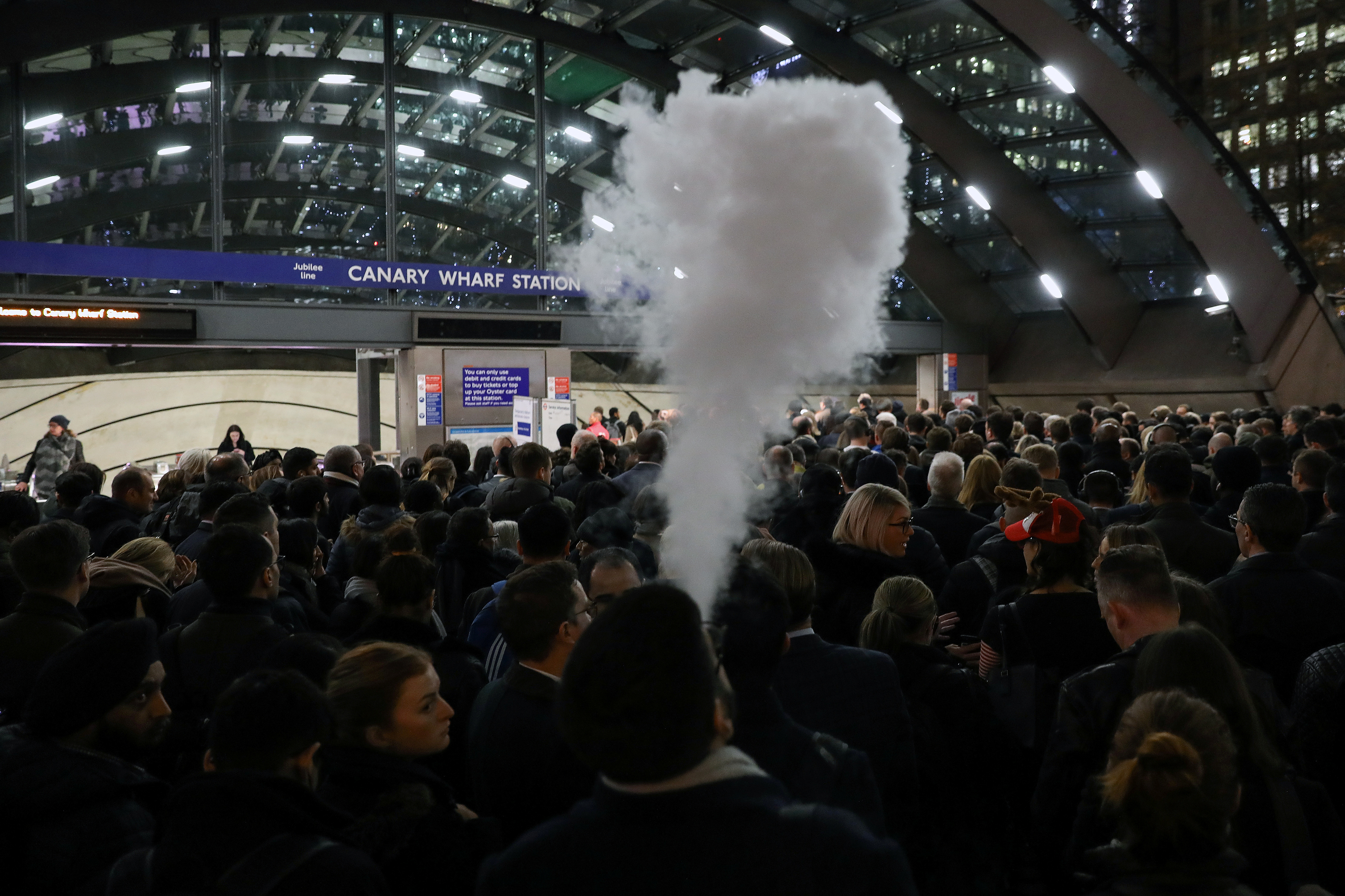 A man smokes an e-cigarette in the queue to Canary Wharf tube station