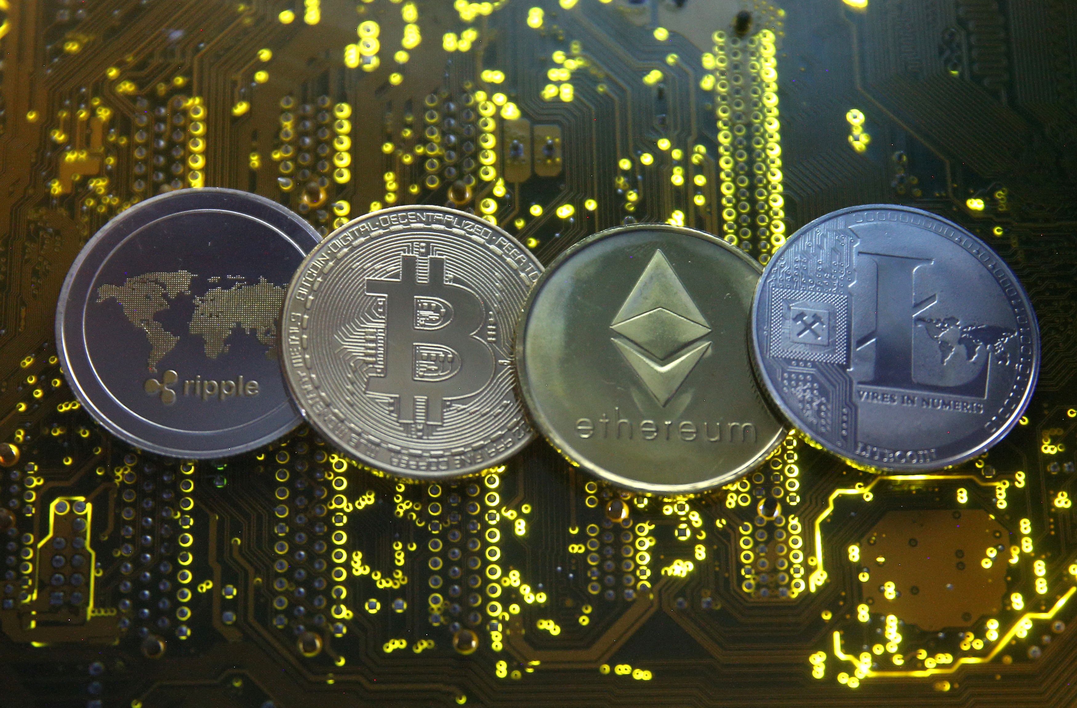 Las representaciones de las monedas virtuales Ripple, Bitcoin, Etherum y Litecoin son visibles en la placa base en esta imagen ilustrativa