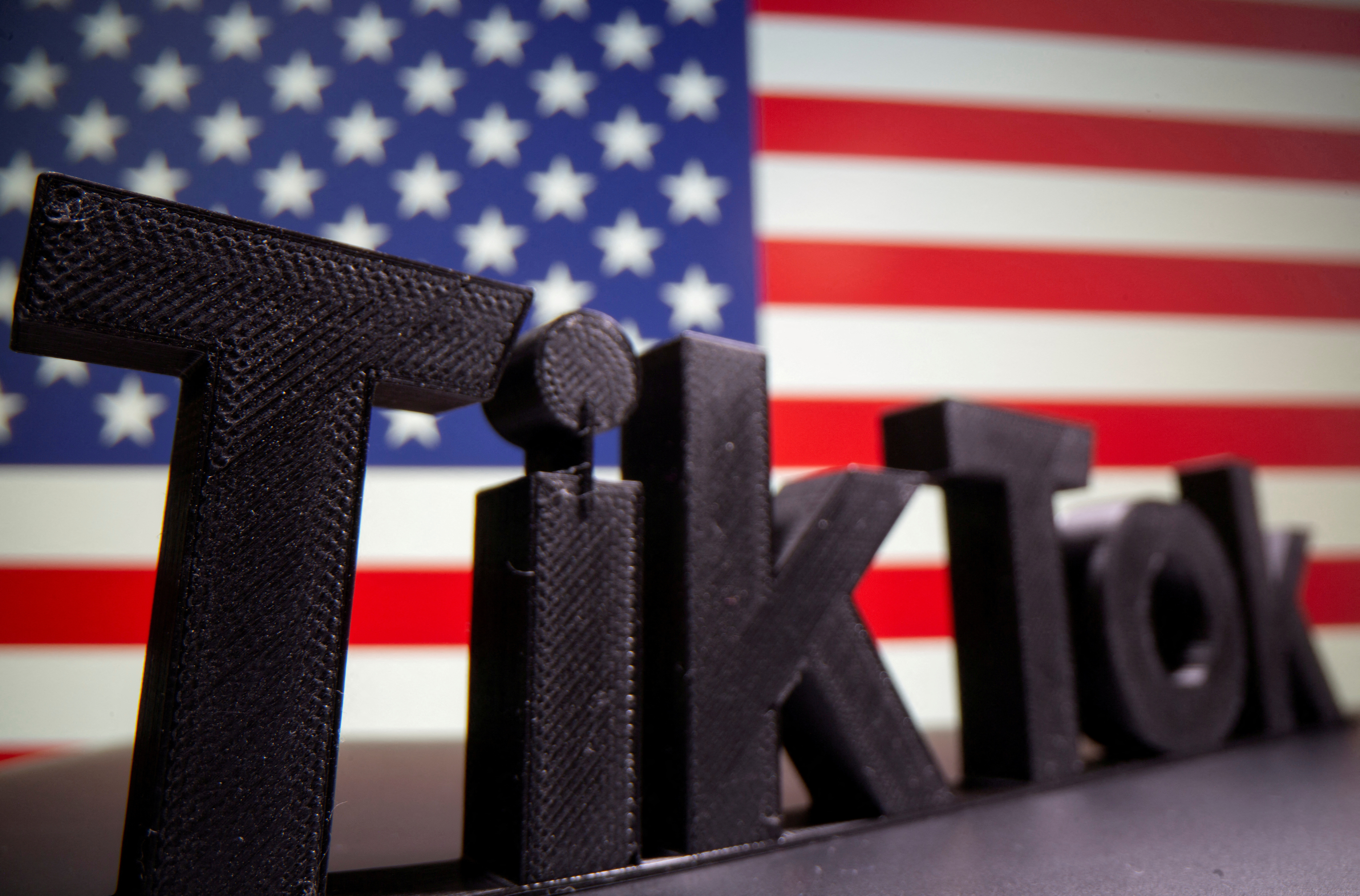 En esta ilustración, se ve un logotipo de Tik Tok impreso en 3D frente a la bandera de EE. UU.