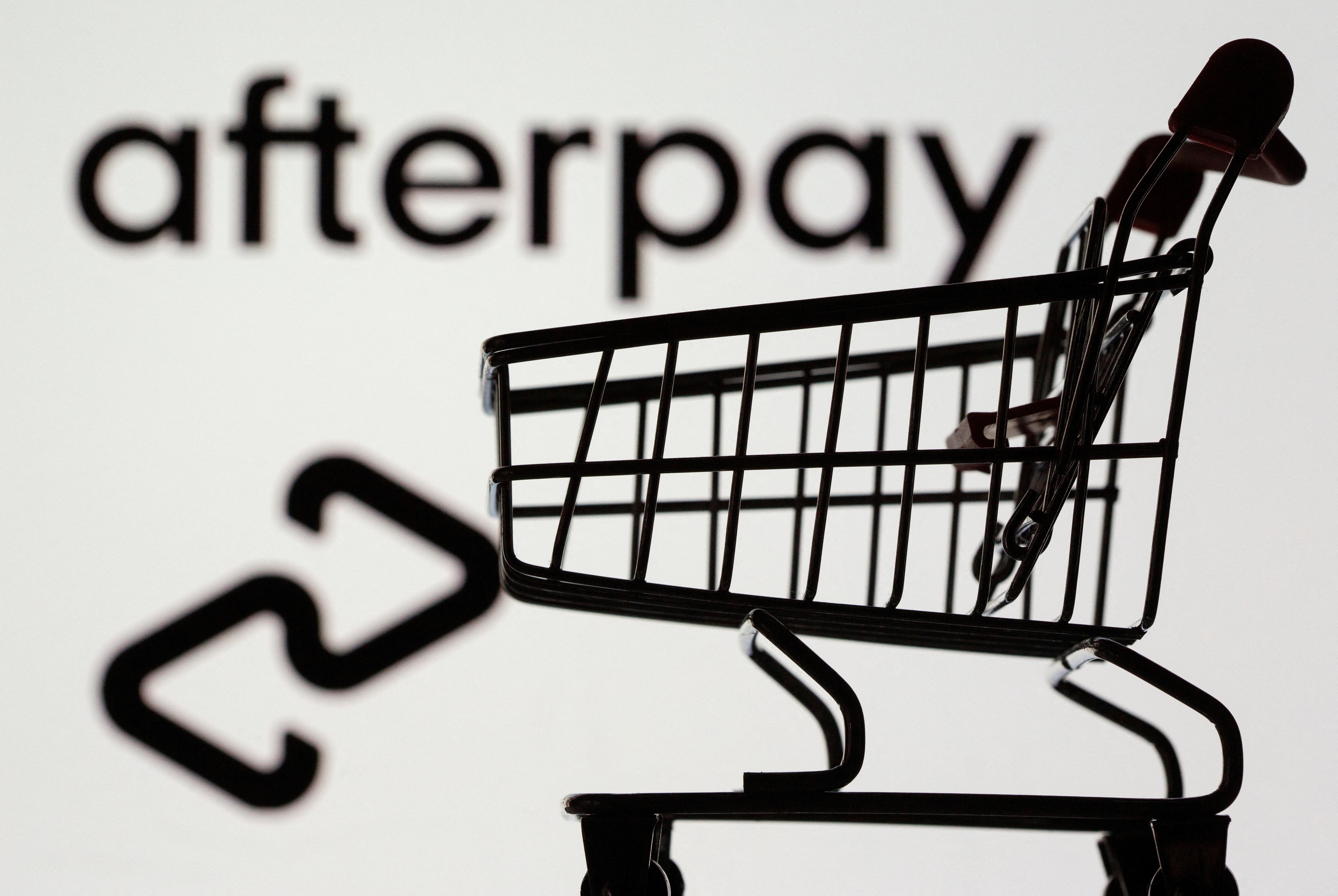 Small toy shopping cart is seen in front of a displayed Afterpay logo in this illustration taken