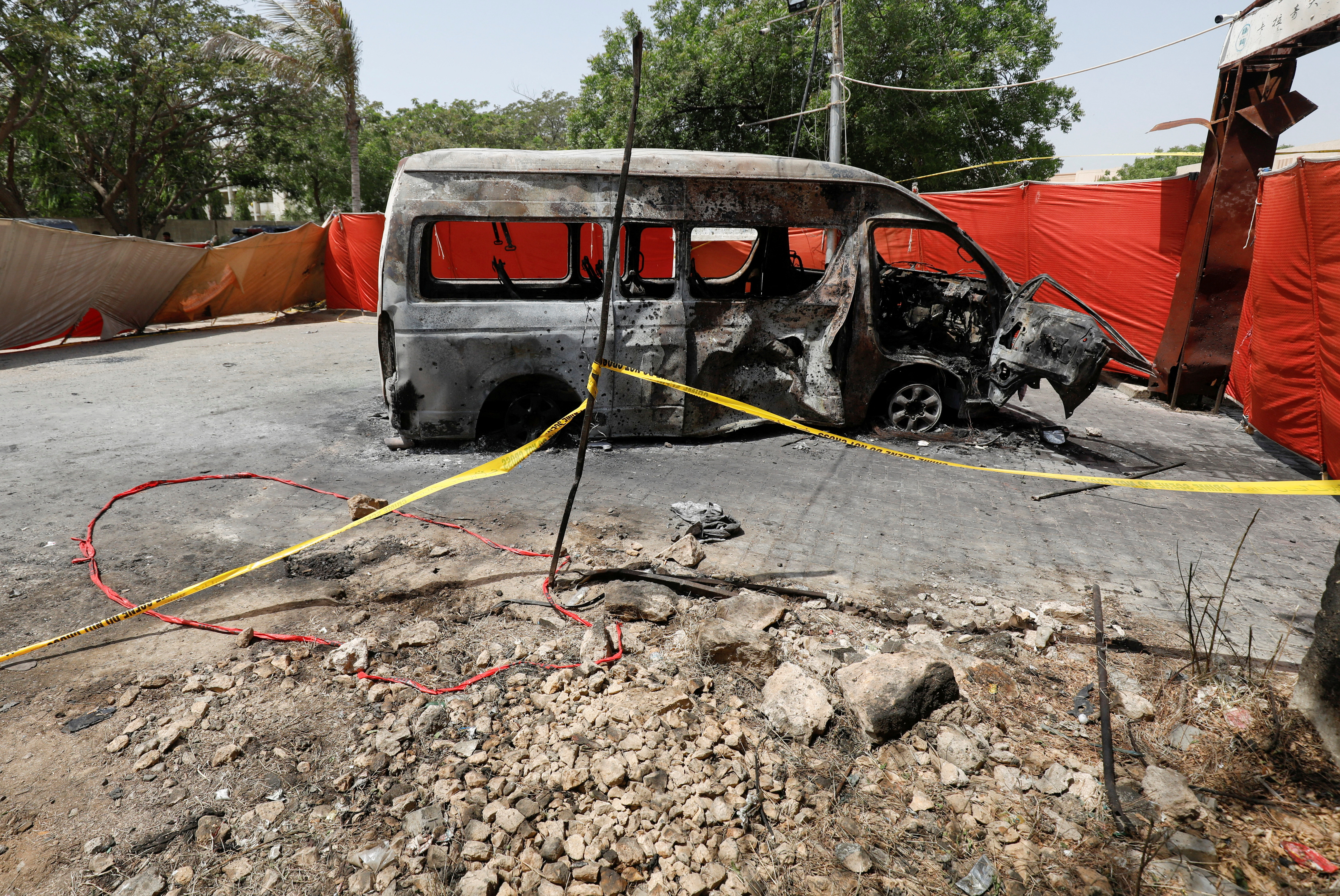 A view of the crater and cordoned area near a damaged passenger van, a day after a suicide blast, at the entrance of the Confucius Institute University of Karachi