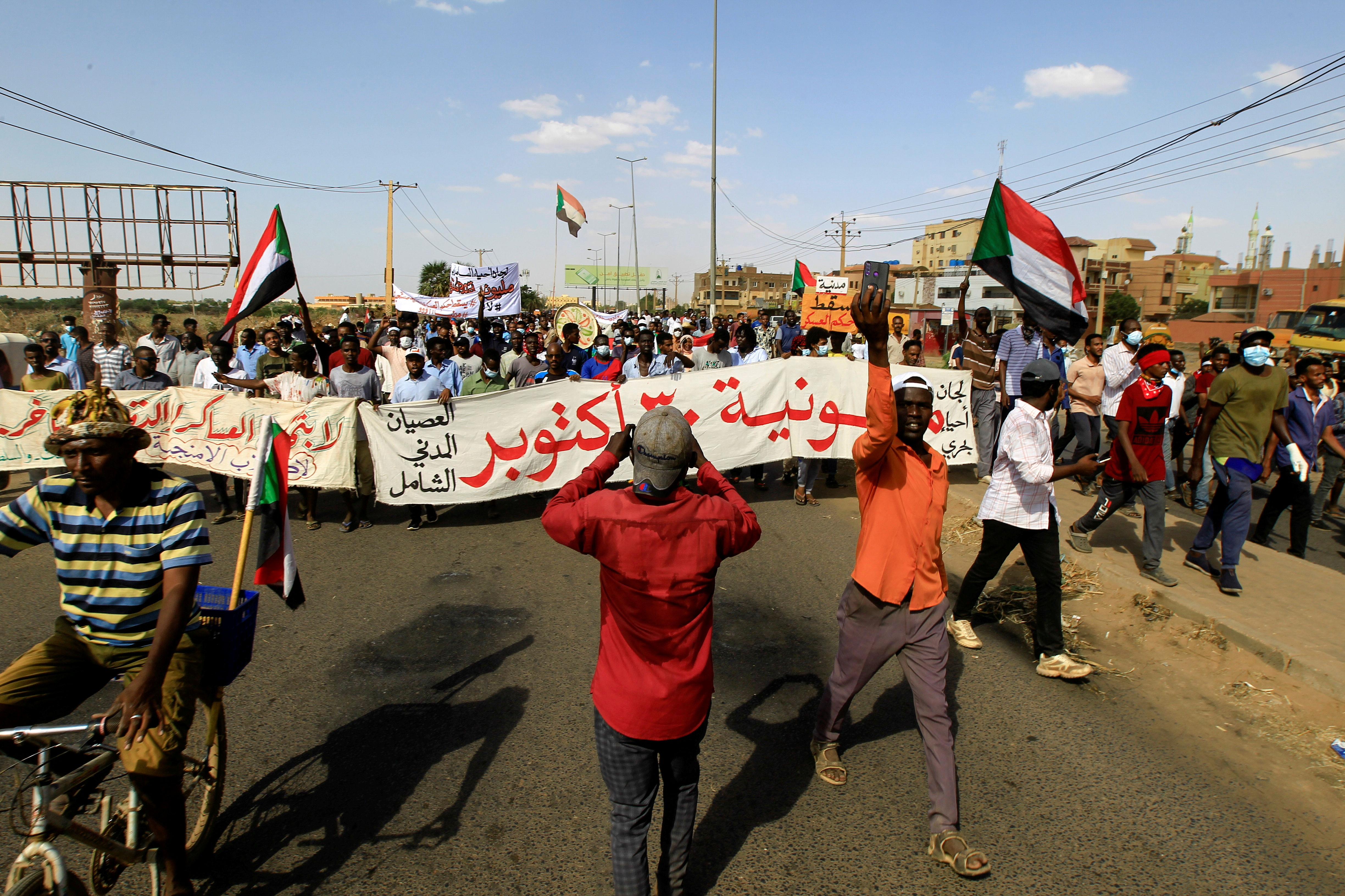 Protesters carry a banner and national flags as they march against the Sudanese military's recent seizure of power and ousting of the civilian government, in the streets of the capital Khartoum, Sudan October 30, 2021. REUTERS/Mohamed Nureldin