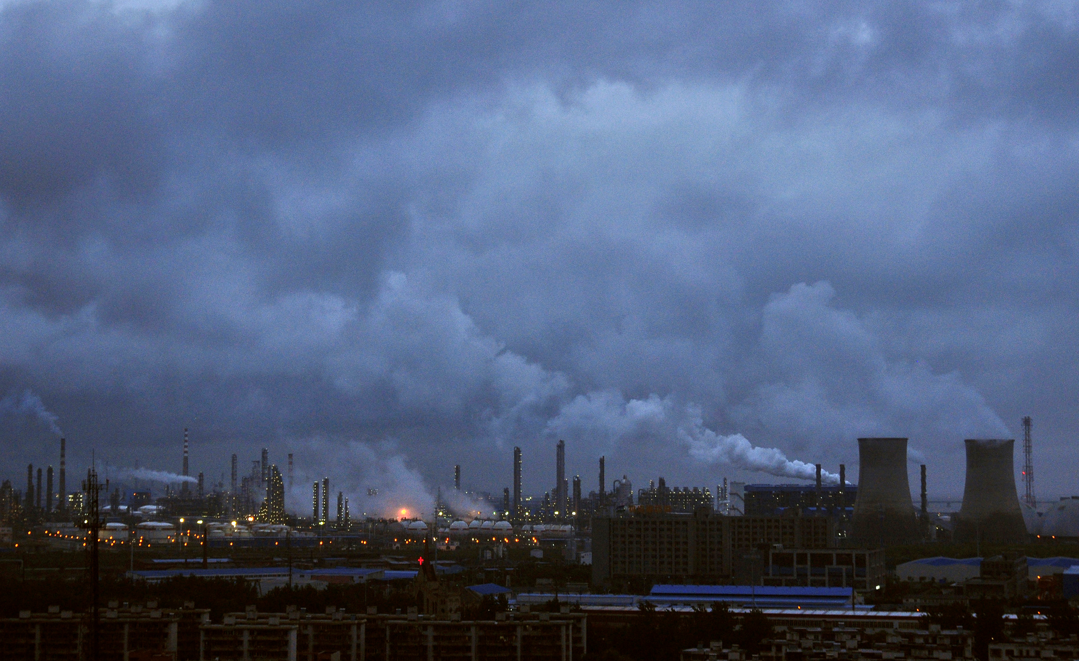 Smoke rises from chimneys and cooling towers of a refinery in Ningbo