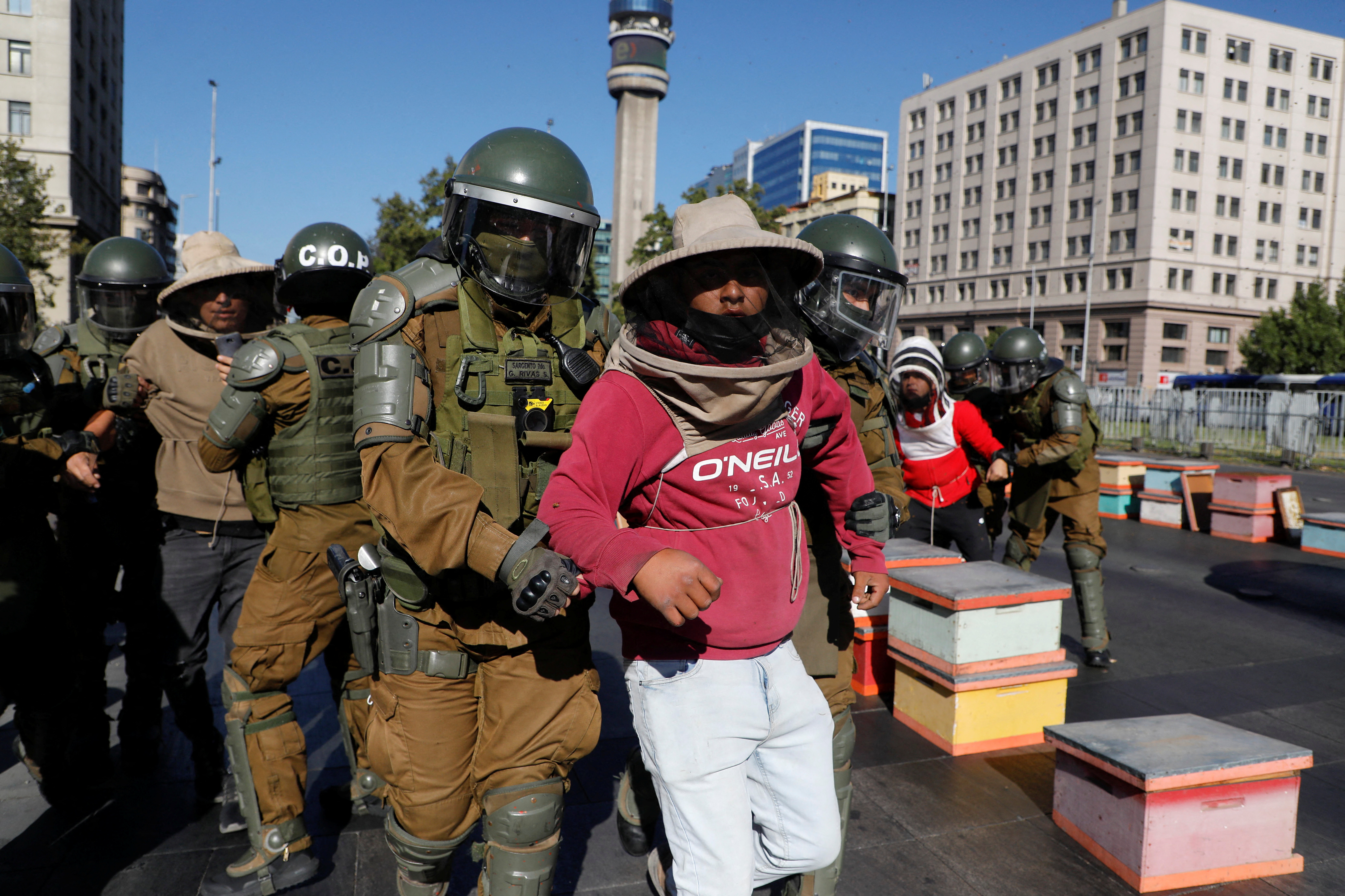 Beekeepers who demanded government measures to face the persistent drought that affects the country are detained by riot police after they blocked the street with honeycombs full of bees in front of the Chilean presidential palace, in Santiago, Chile, January 3, 2022. REUTERS/Dragomir Yankovic 