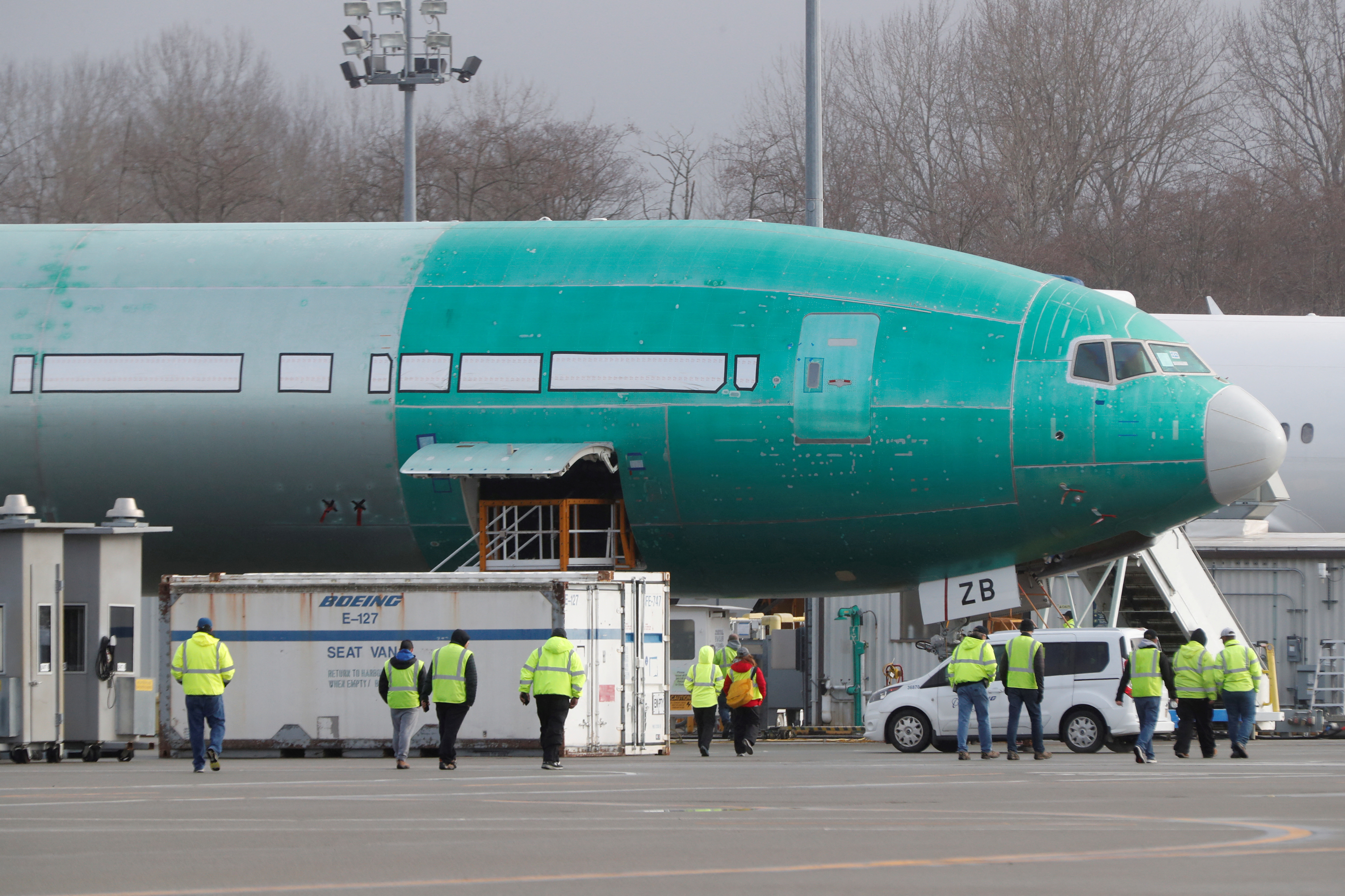 Boeing employees walk near a partially finished Boeing 777X airplane at the company's plant in Everett
